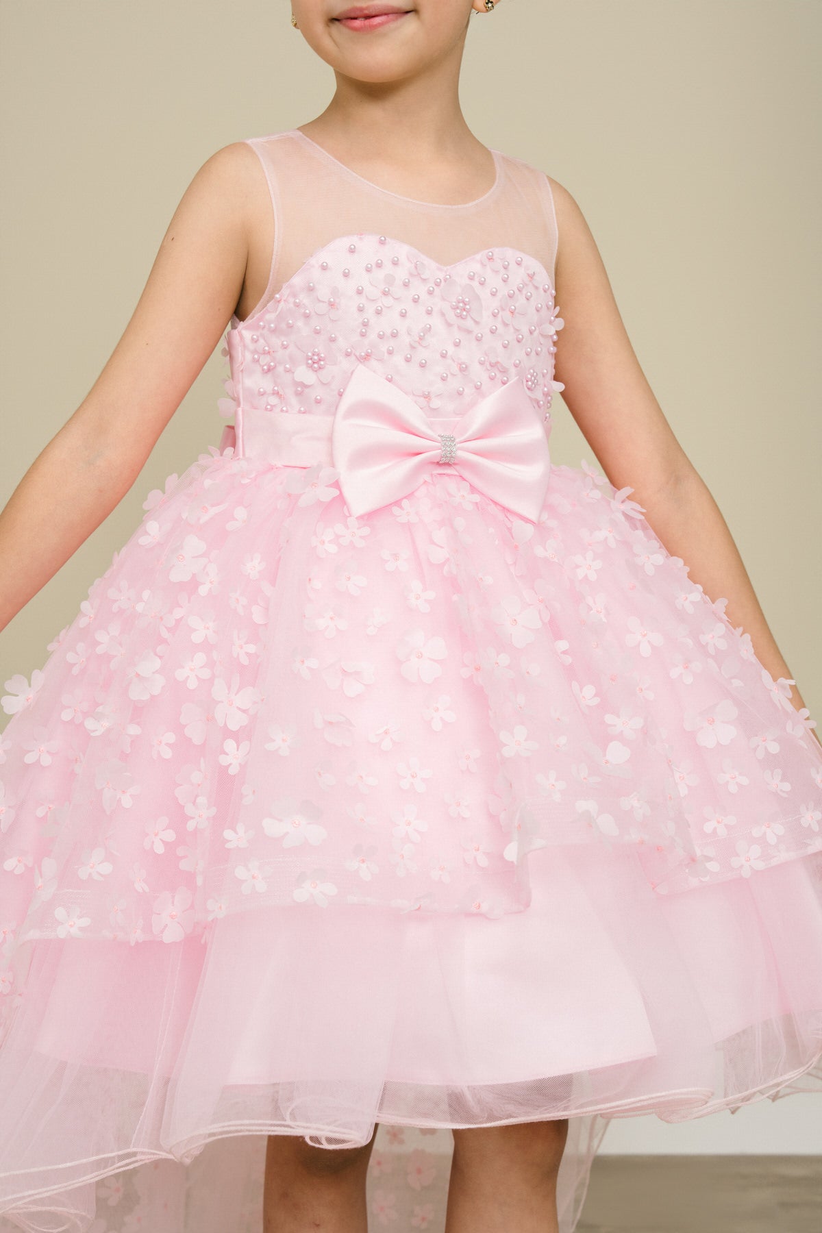 Close-up front view of pink flower girl dress showing 3D floral detail and bodice texture.