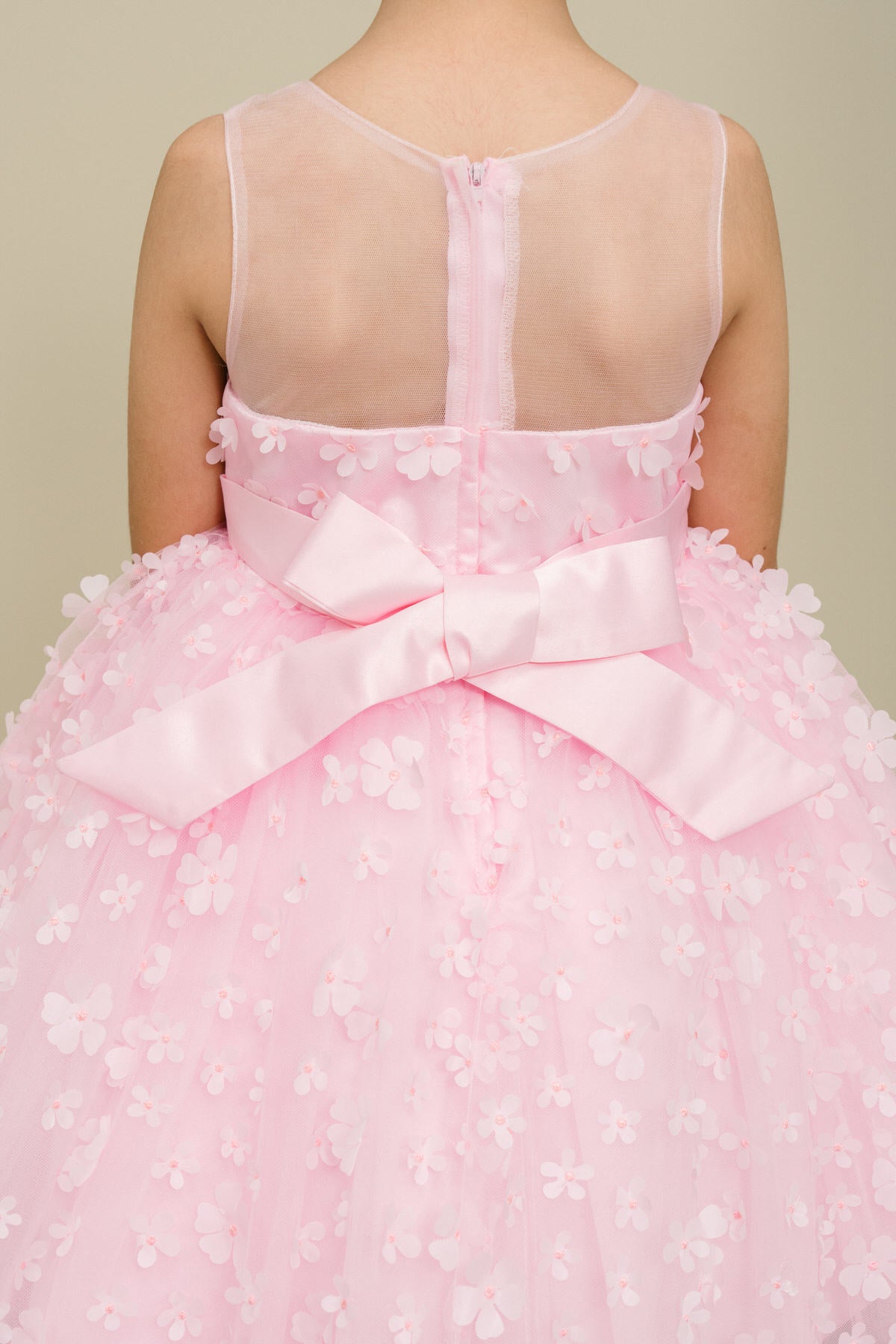 Close-up back view of pink flower girl dress showing 3D floral detail and bodice texture.