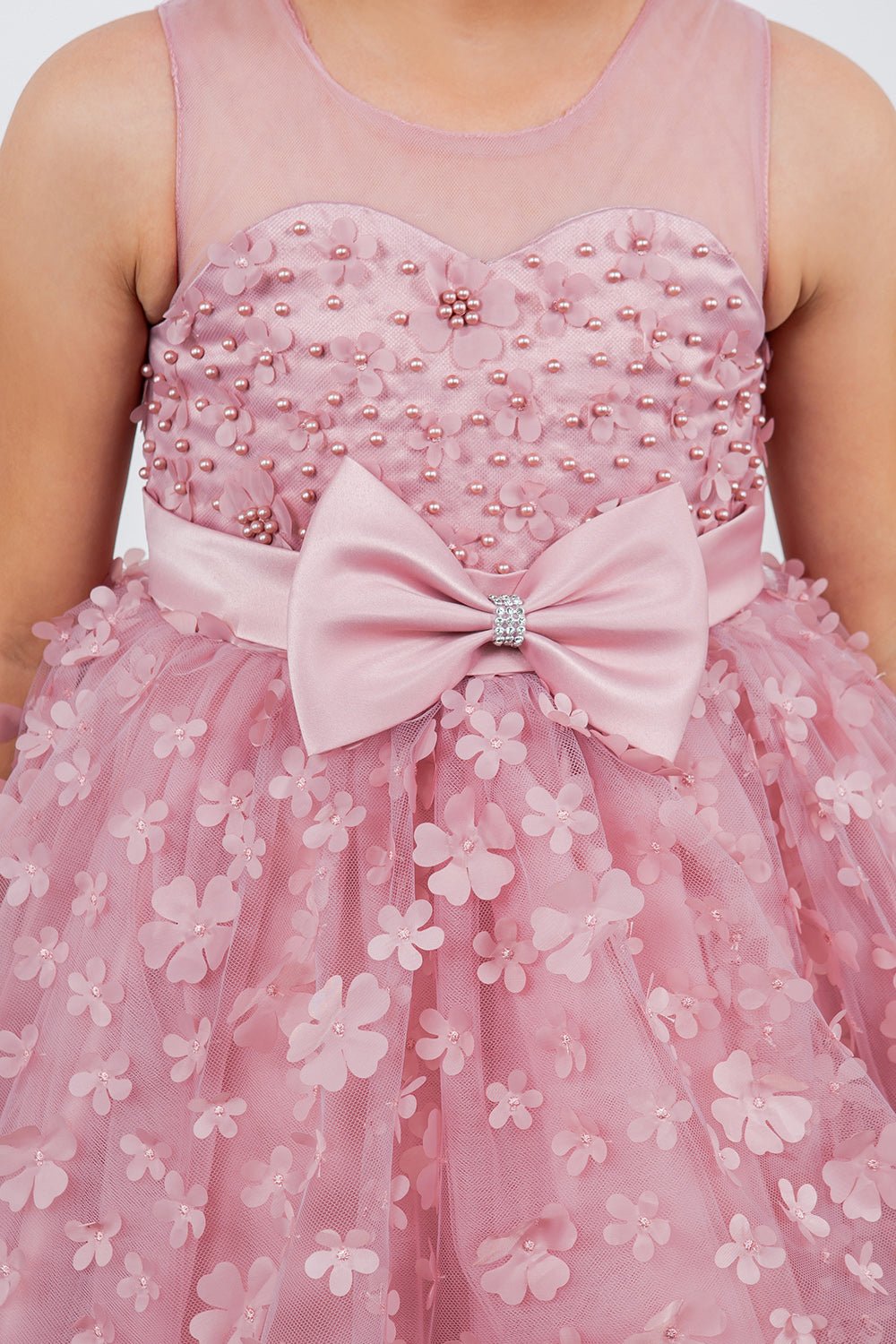 Close-up front view of dusty pink flower girl dress showing 3D floral detail and bodice texture.