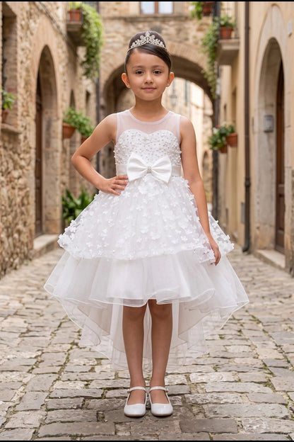 Shown in a front view, the White flower girl dress has sheer neckline, waist bow and floral high-low skirt.