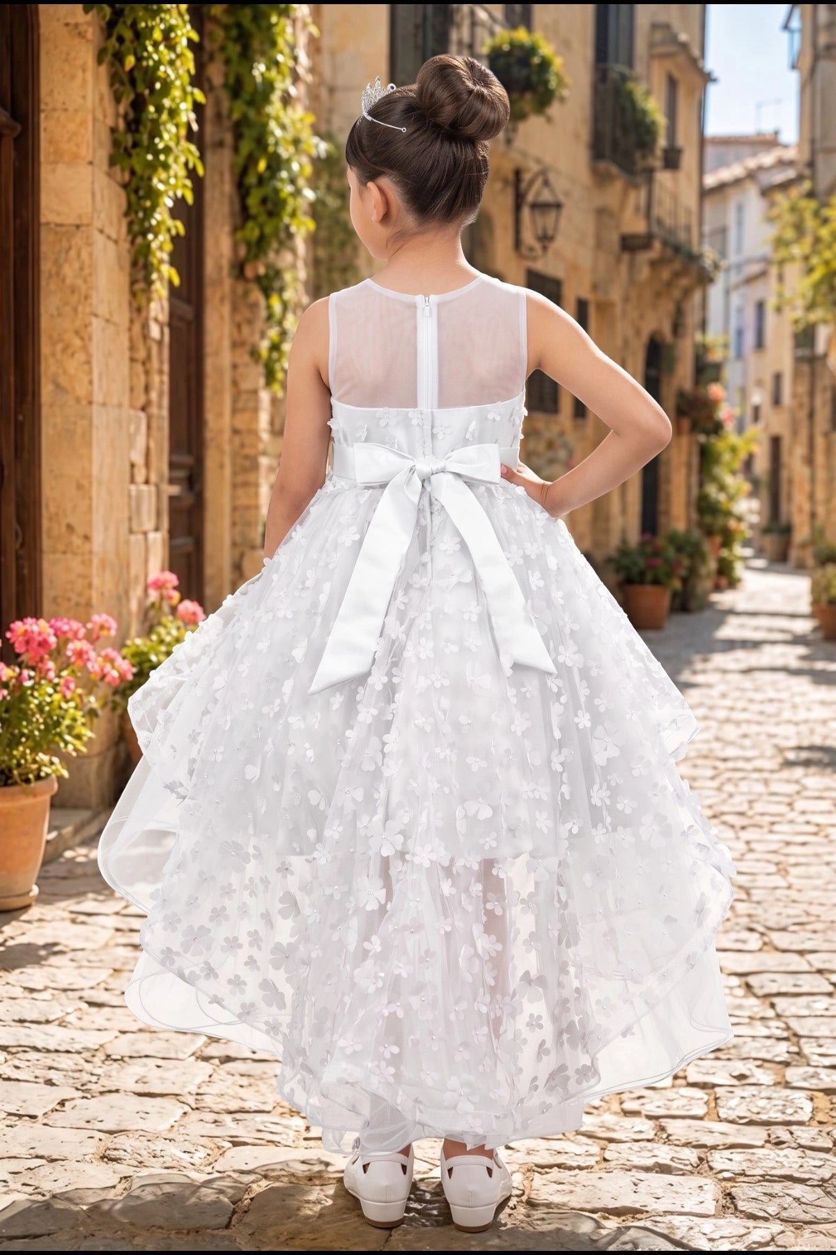 Displayed in a back view, the White flower girl dress has sheer back and satin bow above the floral tulle train.