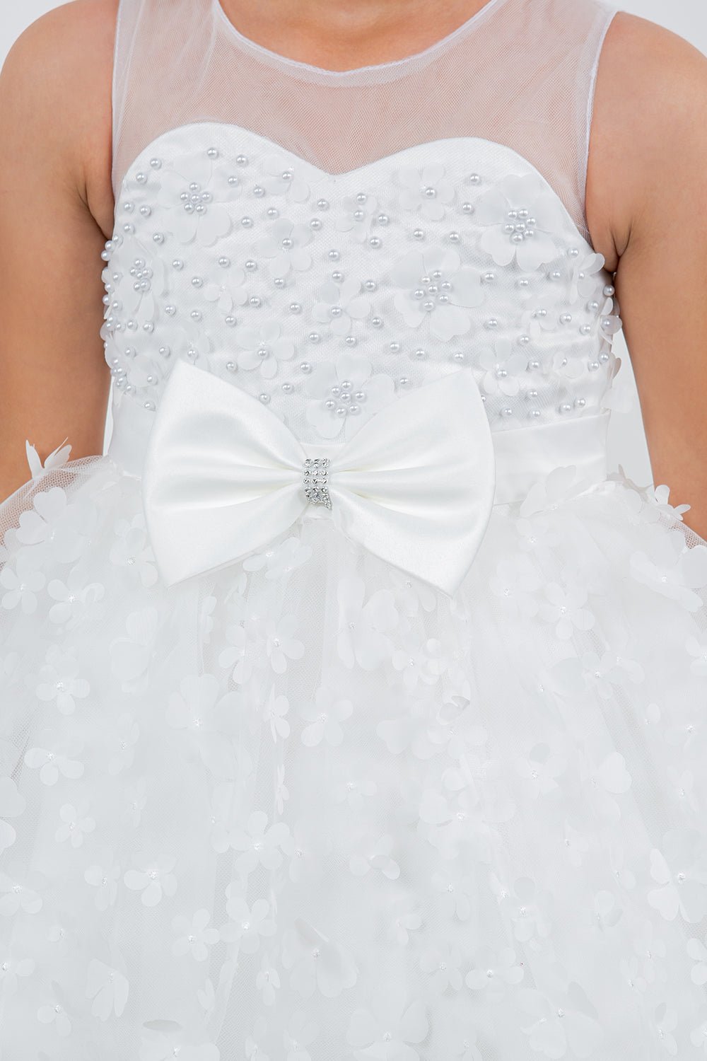 Close-up front view of white flower girl dress showing 3D floral detail and bodice texture.