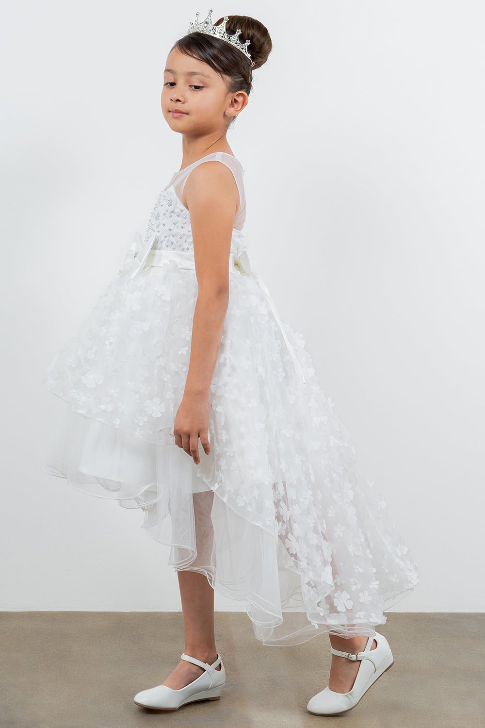 White flower girl dress side view highlighting hi-low silhouette and elegant structure.