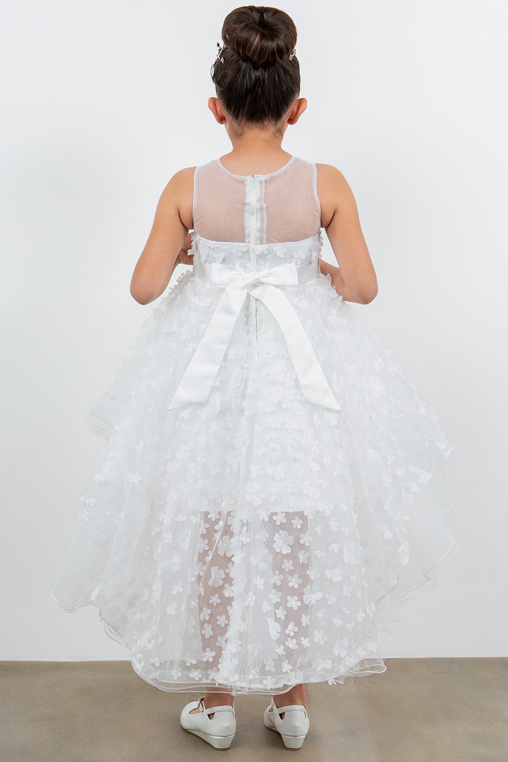 Back view of white flower girl dress at formal event.