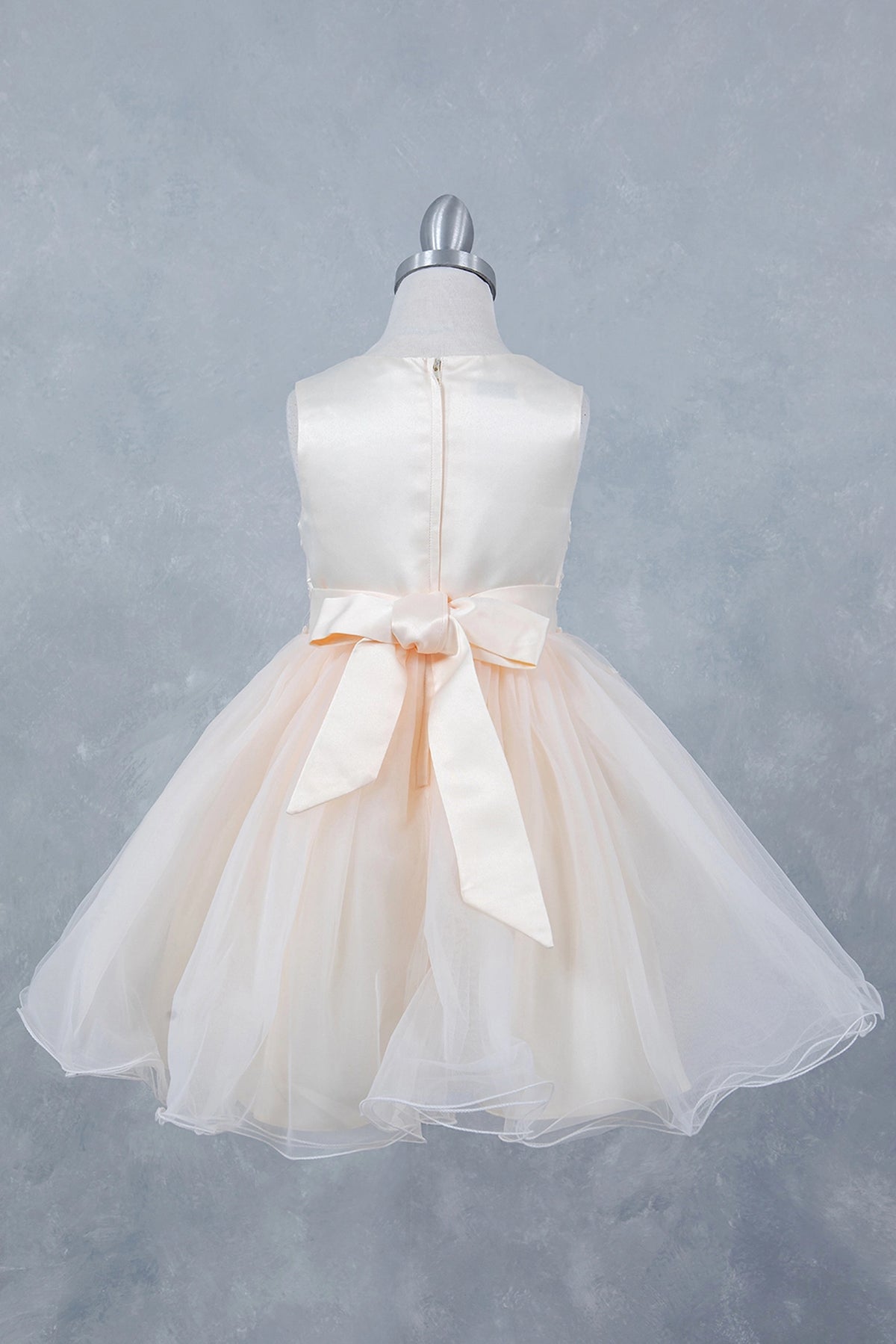 Finished details of a satin waist bow distinguish the Champagne kids party dress.