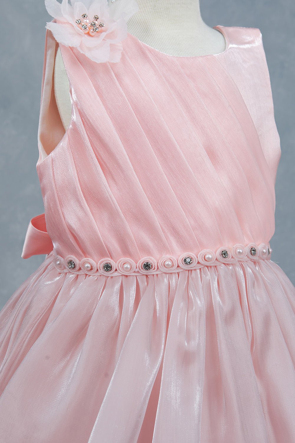 Close-up front view of peach flower girl dress showing beadwork floral applique and pearl waist.