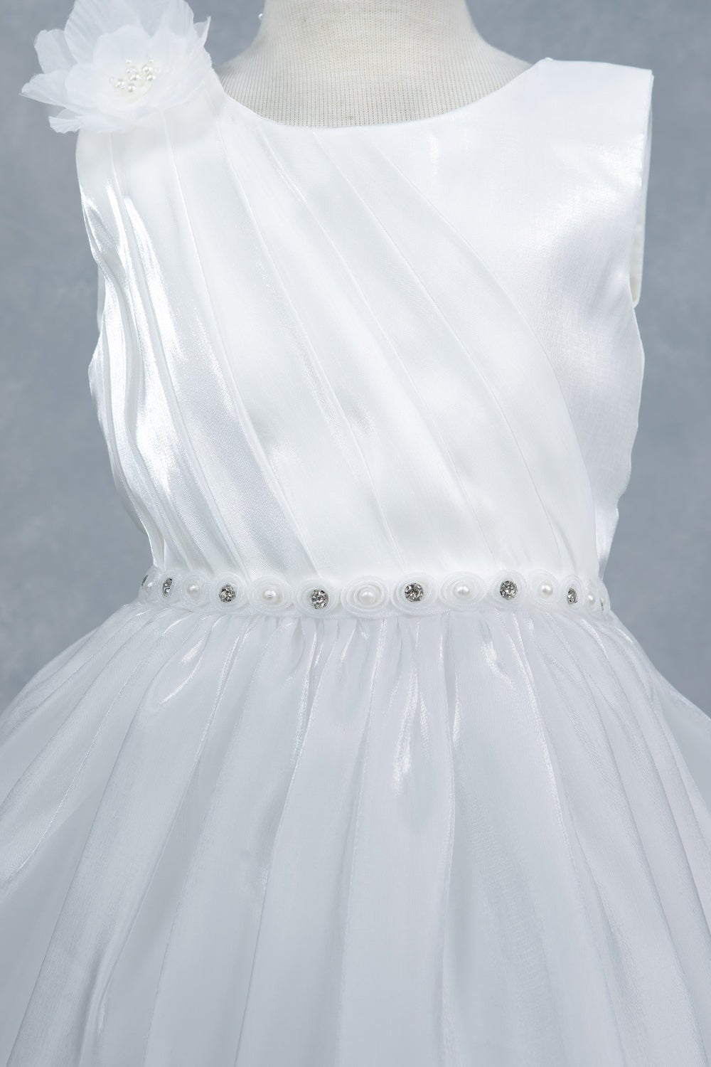 Close-up front view of white flower girl dress showing beadwork floral applique and pearl waist.