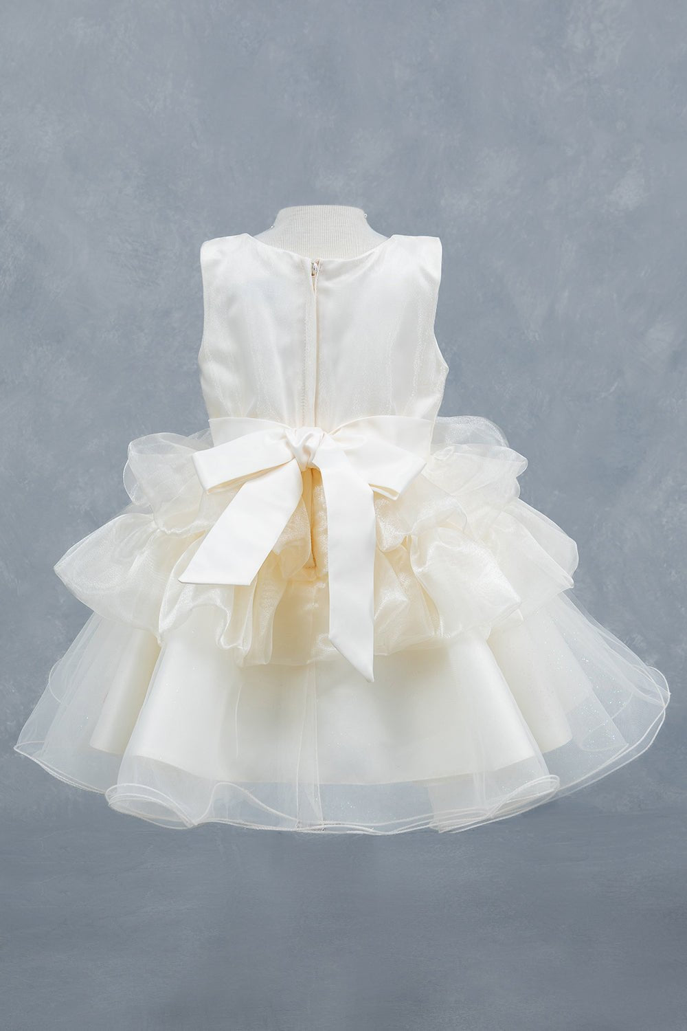 White flower girl dress back view highlighting layered tulle and soft silhouette.