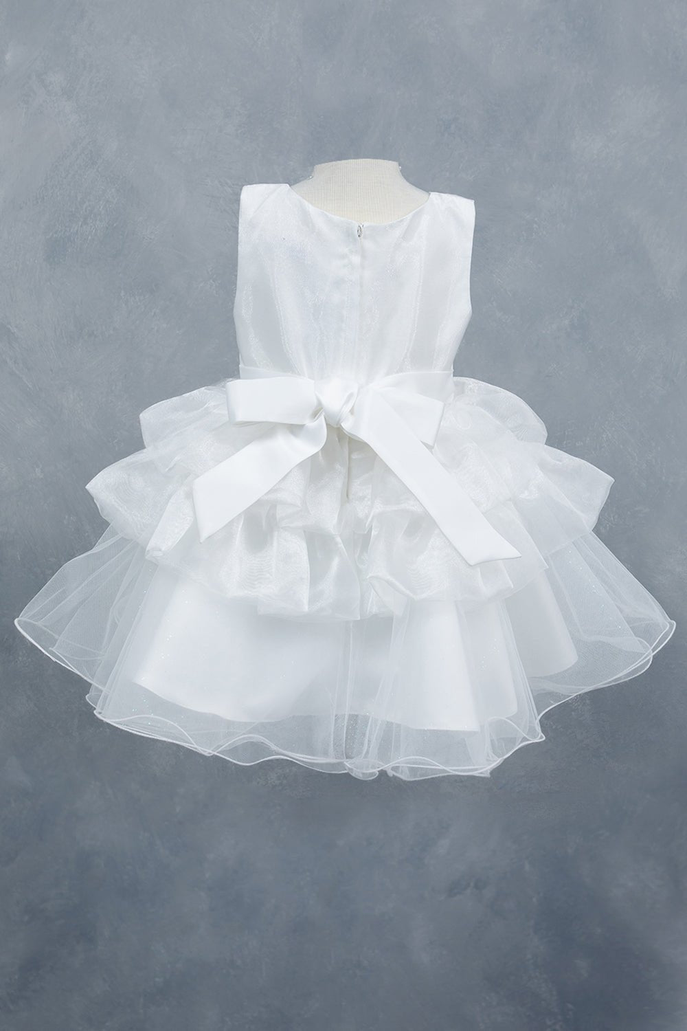 White flower girl dress back view highlighting layered tulle and soft silhouette.