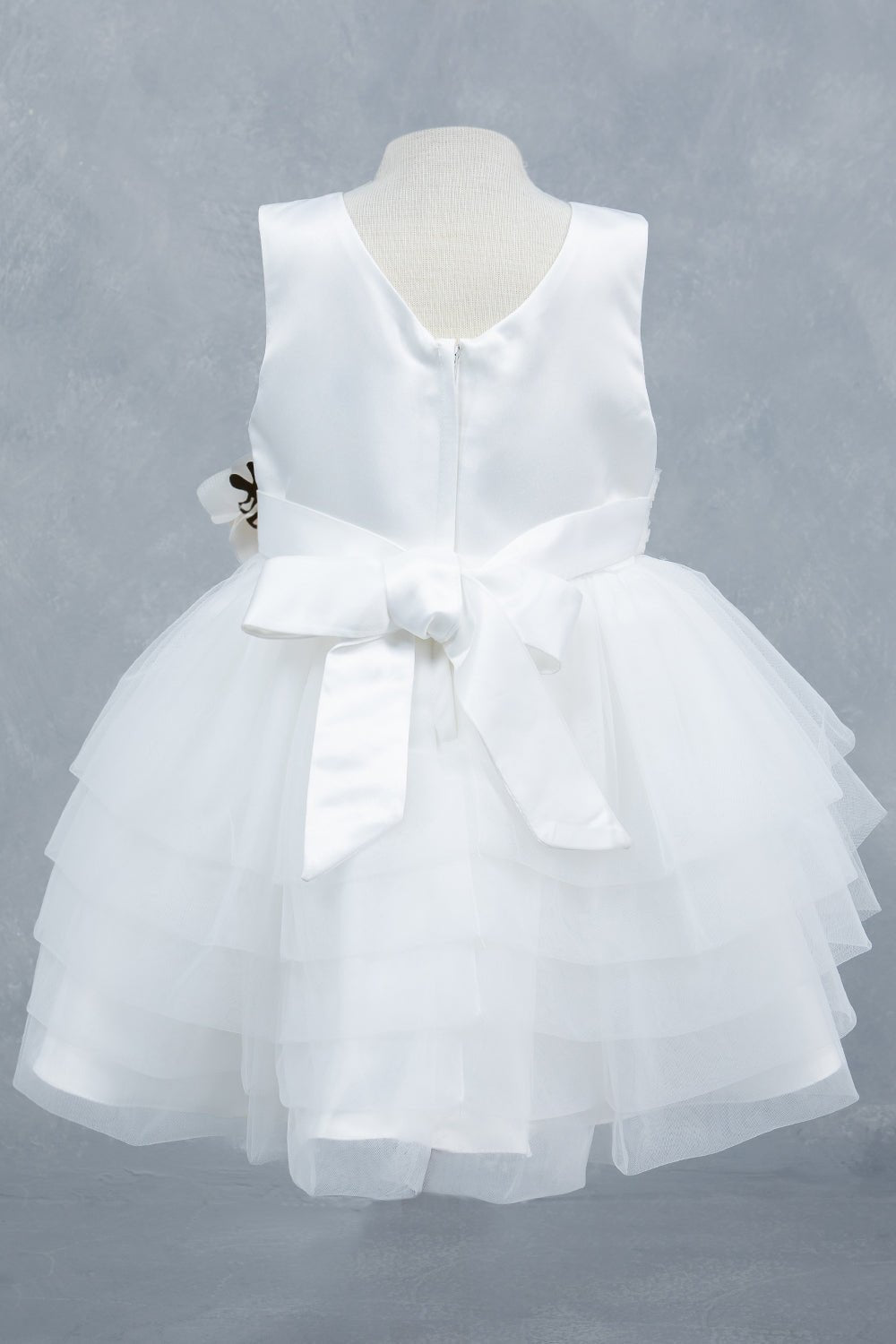 White flower girl dress back view highlighting layered tulle and soft silhouette.
