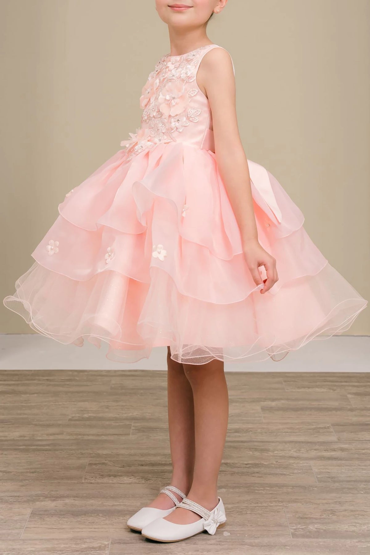 A peach blush flower girl dress with floral details.
