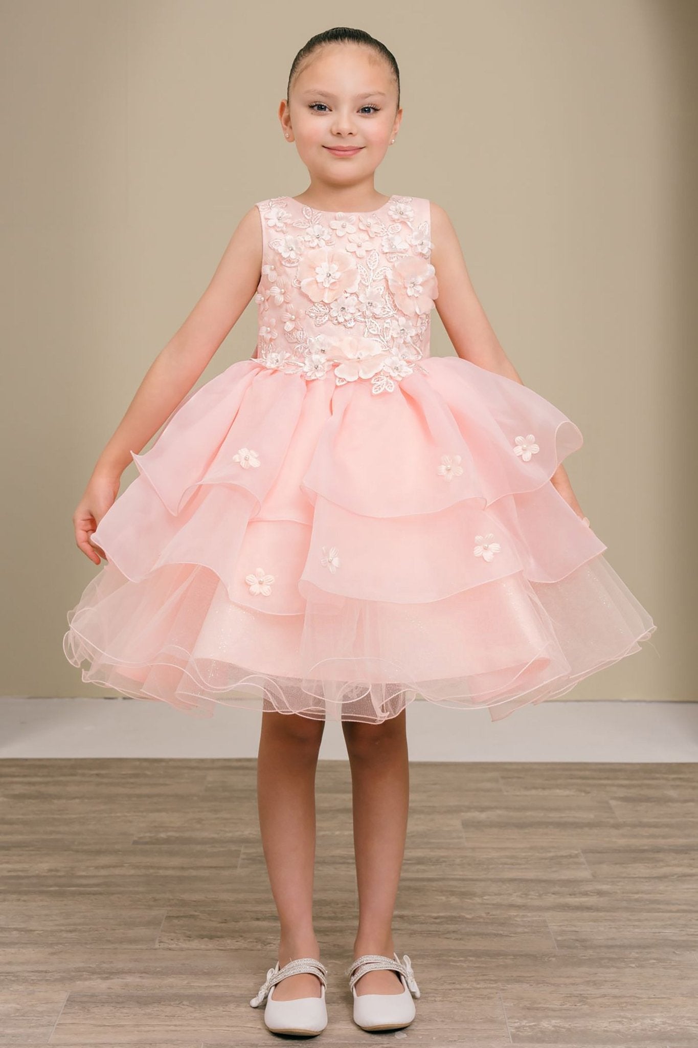 Young girl wearing a peach blush floral dress on a plain background