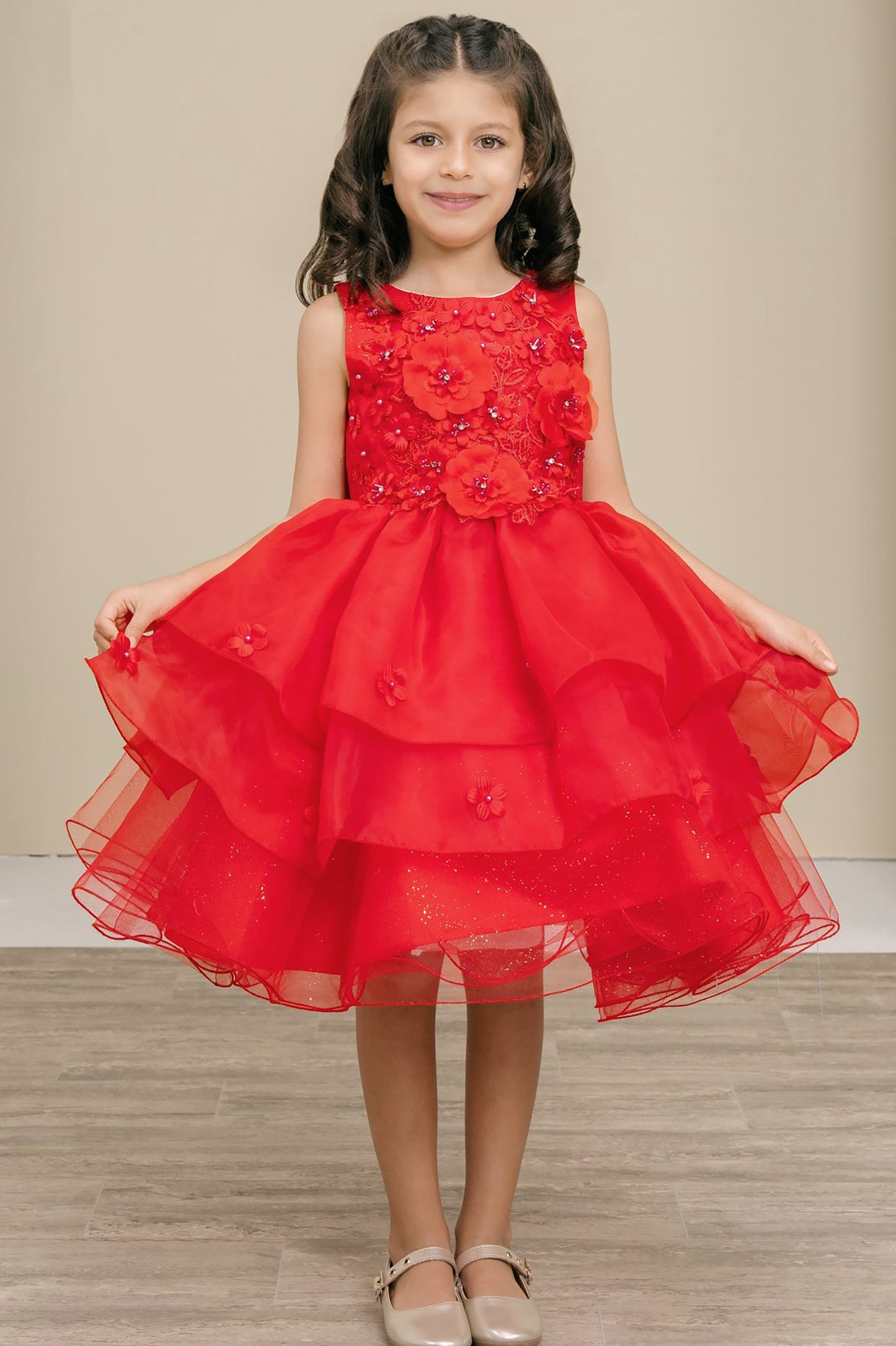 Young girl wearing a red dress with floral details on a neutral background