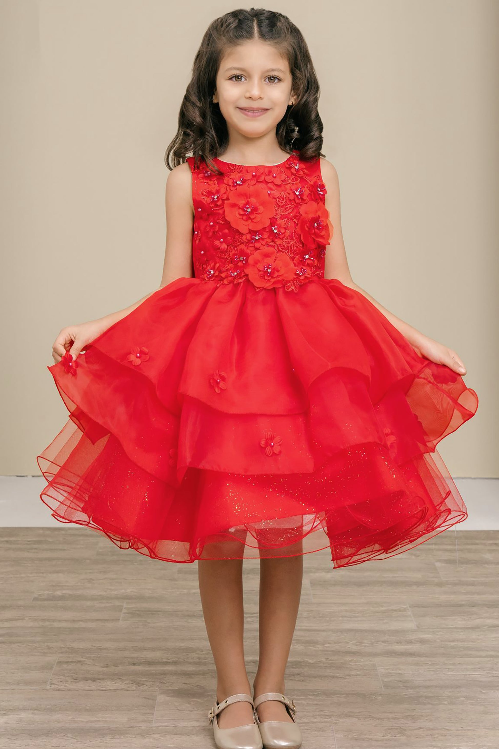 Young girl wearing a red dress with floral details on a neutral background