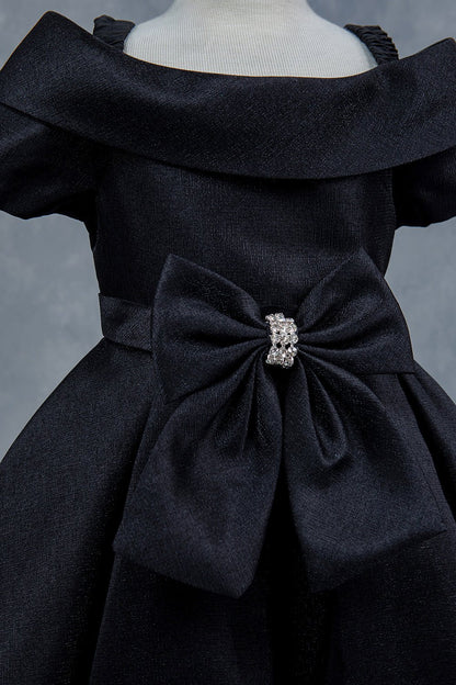Close-up front view of black dress showing rhinestone bow detail and collar