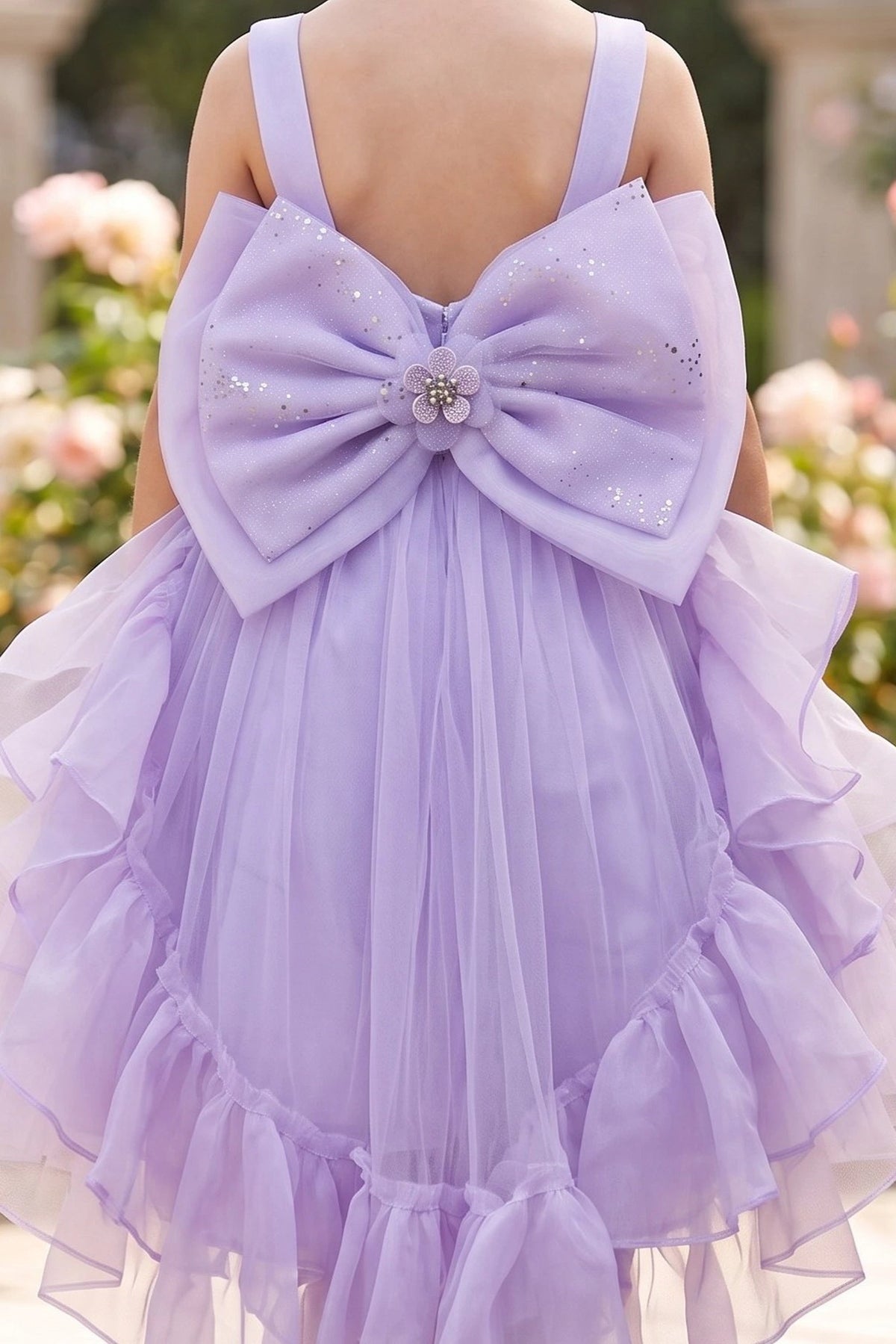 A Lilac flower girl dress showing oversized satin bow above ruffled tulle.