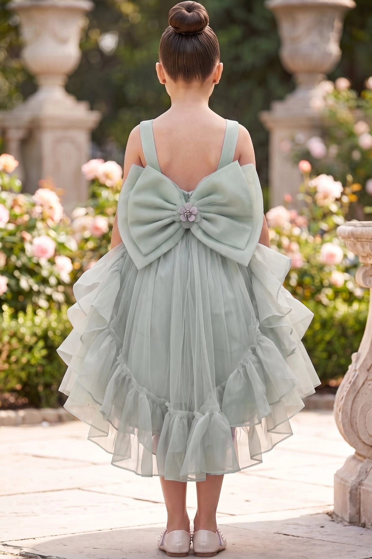 A Sage flower girl dress showing open back with bow and ruffled tulle hem.