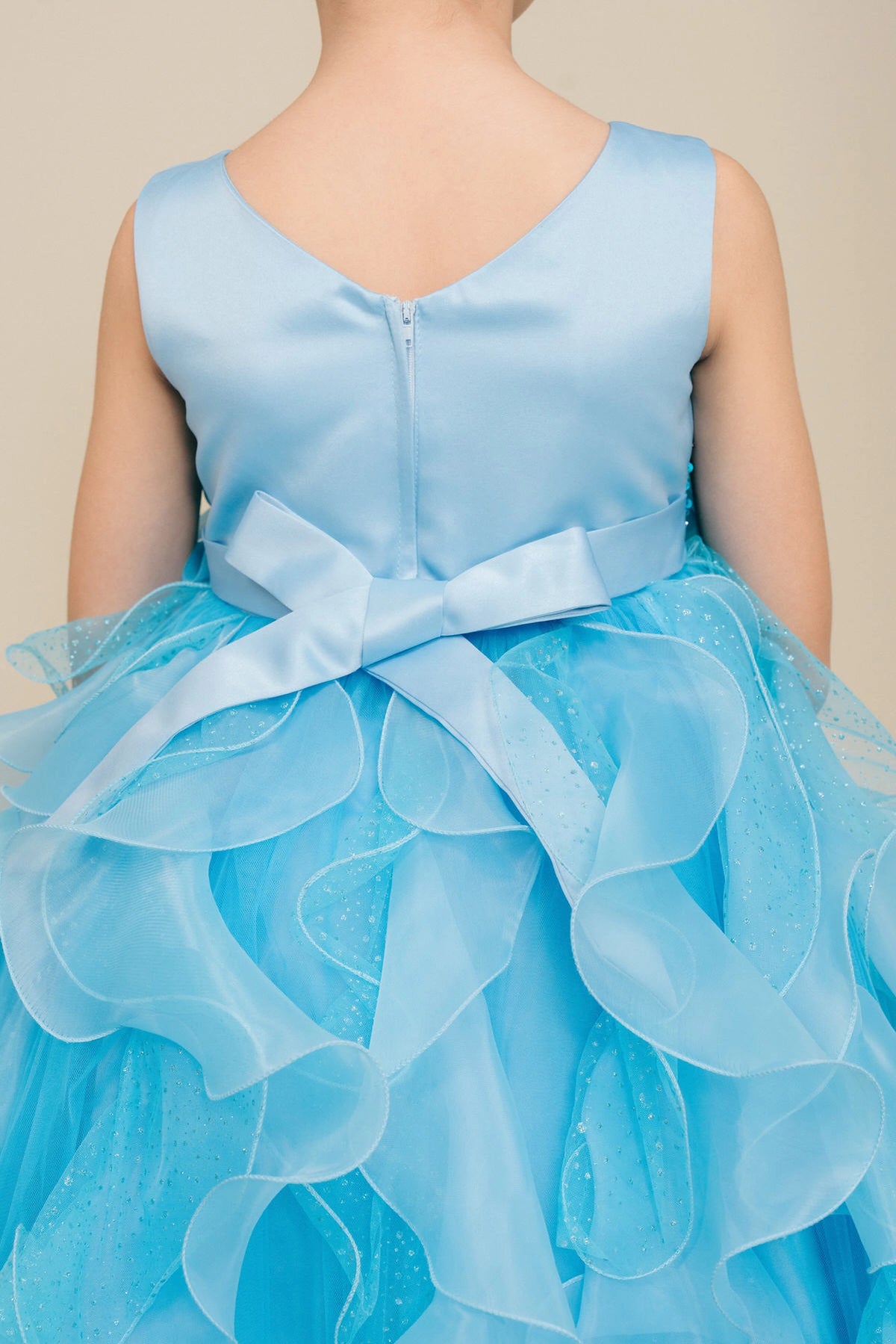 Detailed by a bow above petal-shaped ruffles, the Blue kids party dress reveals its construction.
