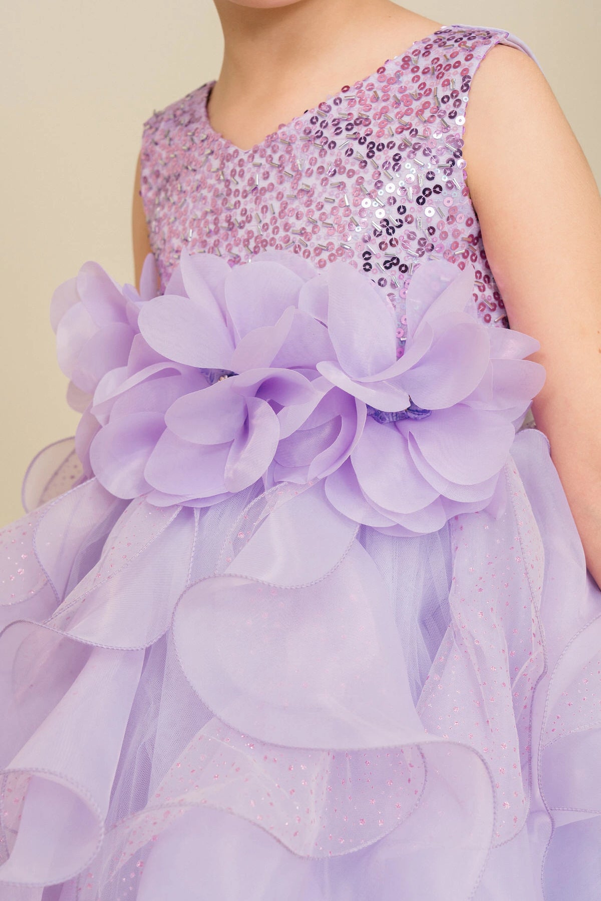 Detailed by petal-shaped skirt ruffles, the Lilac kids party dress reveals its construction.