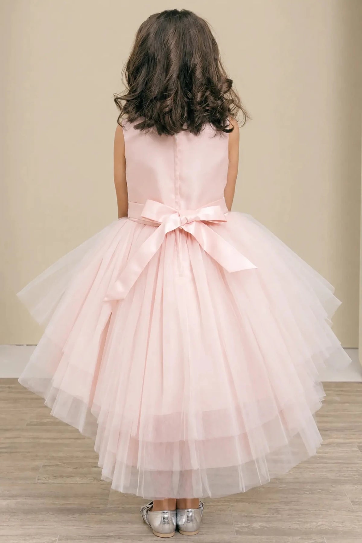 Blush flower girl dress with satin bodice, satin bow back, and layered tulle skirt.