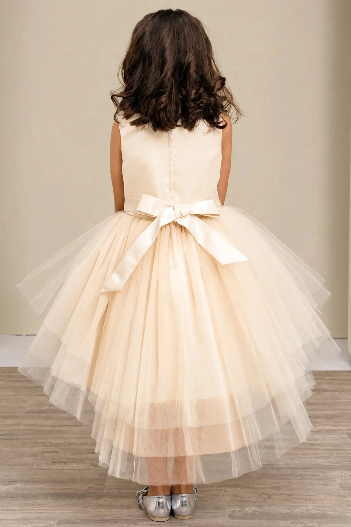 Champagne flower girl dress with satin bodice, satin bow back, and layered tulle skirt.
