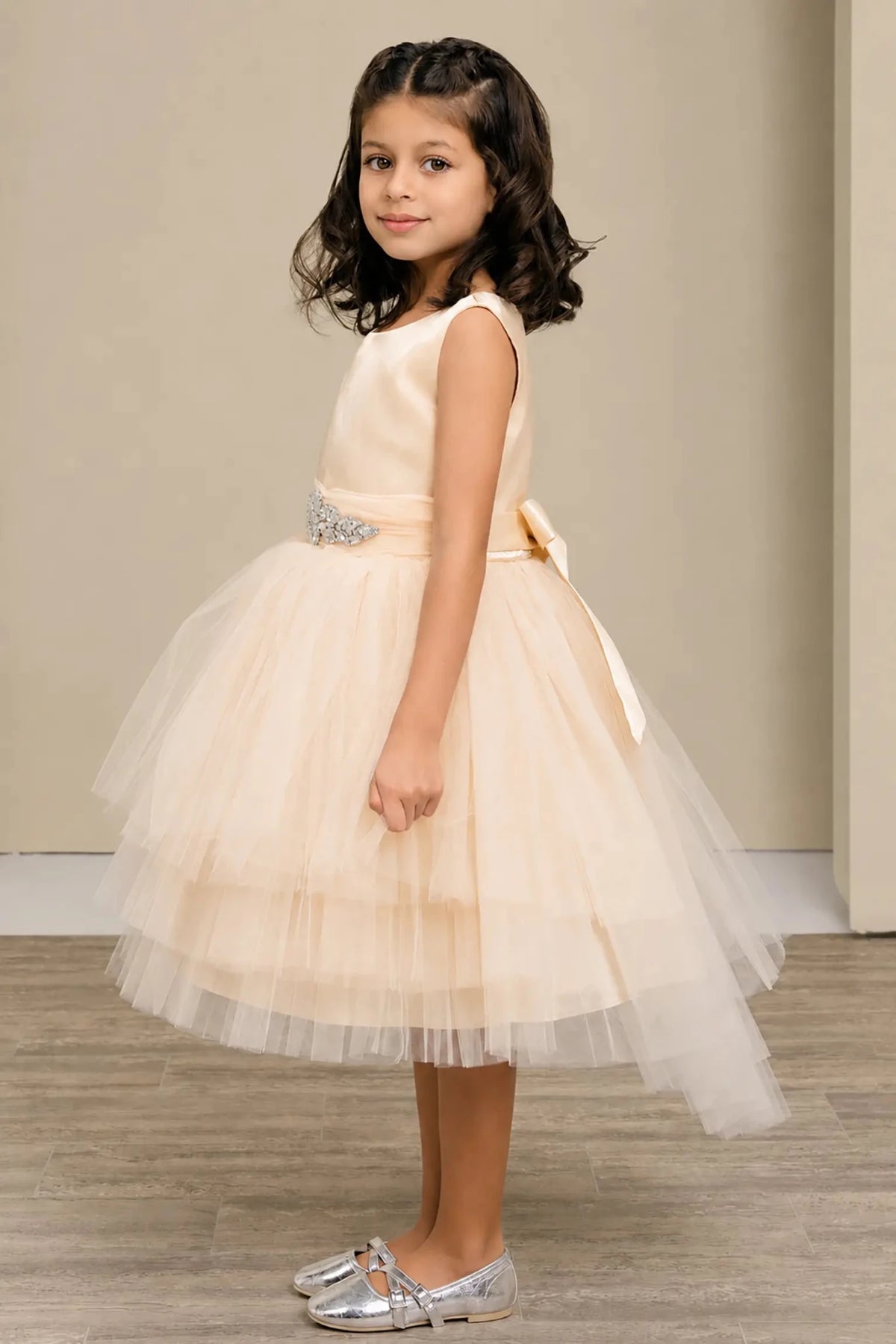 Champagne flower girl dress with satin bodice, rhinestone waistband, satin bow back, and layered tulle skirt.