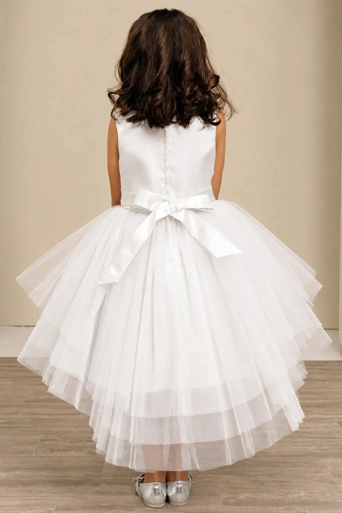 White flower girl dress with satin bodice, satin bow back, and layered tulle skirt.