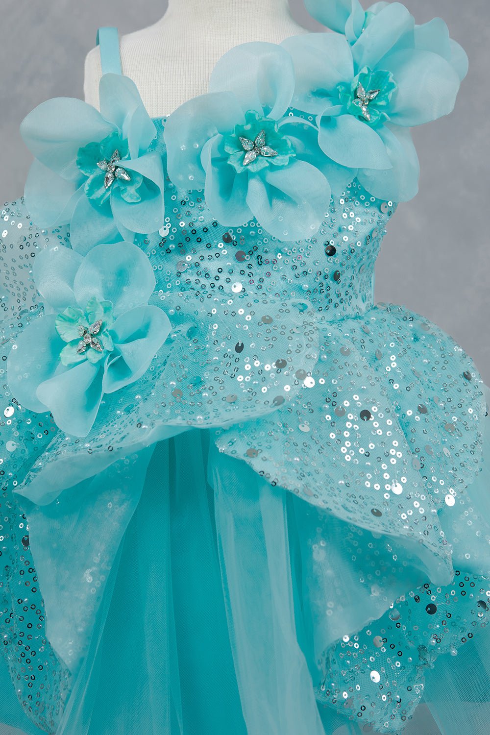 Close-up front view of blue flower girl dress showing shimmering fabric and bow accent.