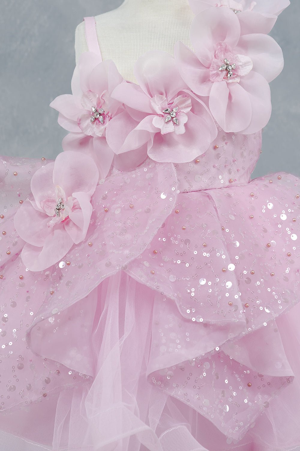 Close-up front view of pink dress showing crystal floral detail and sequin texture