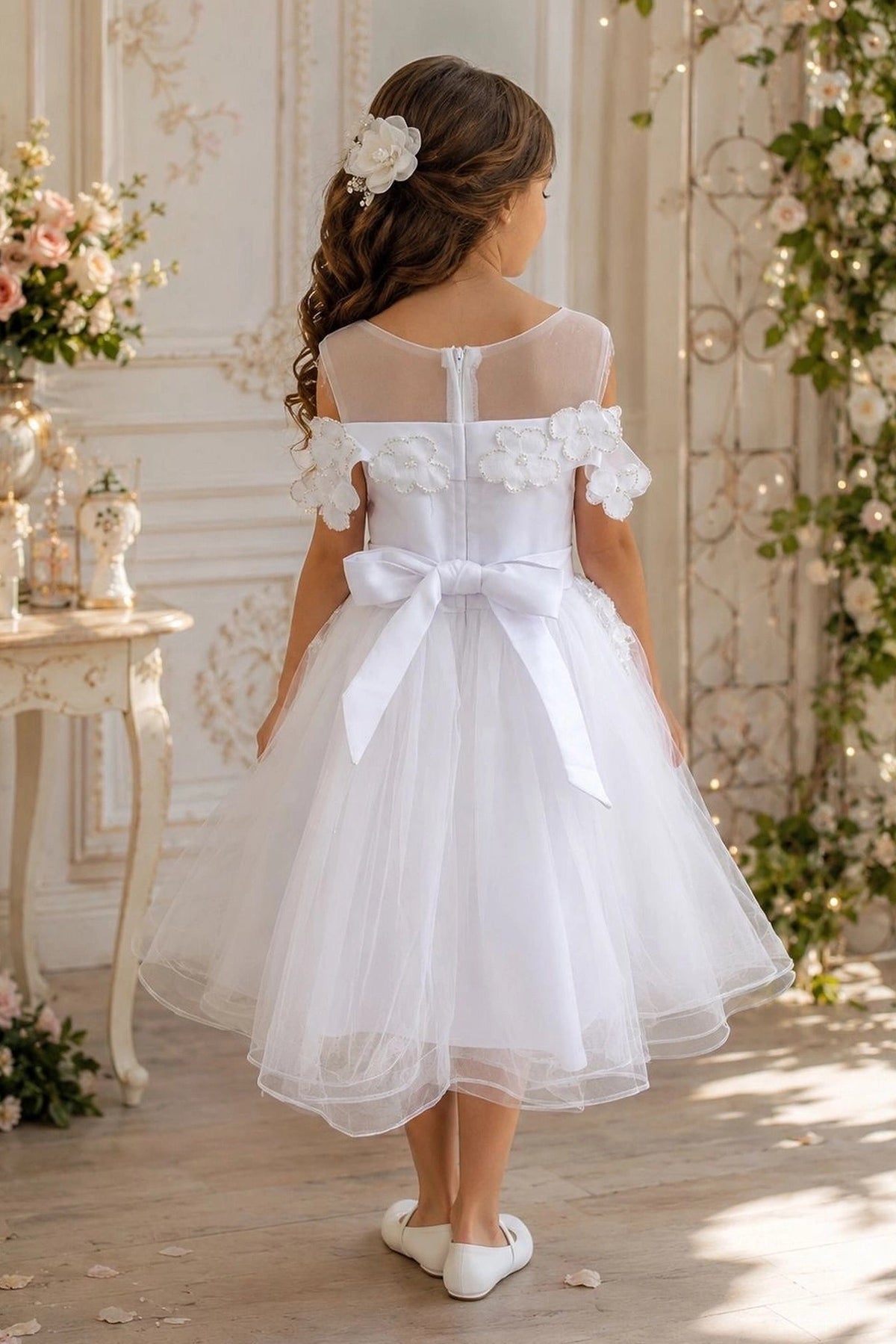 A Off-White flower girl dress showing back sash bow above the layered tulle hem.