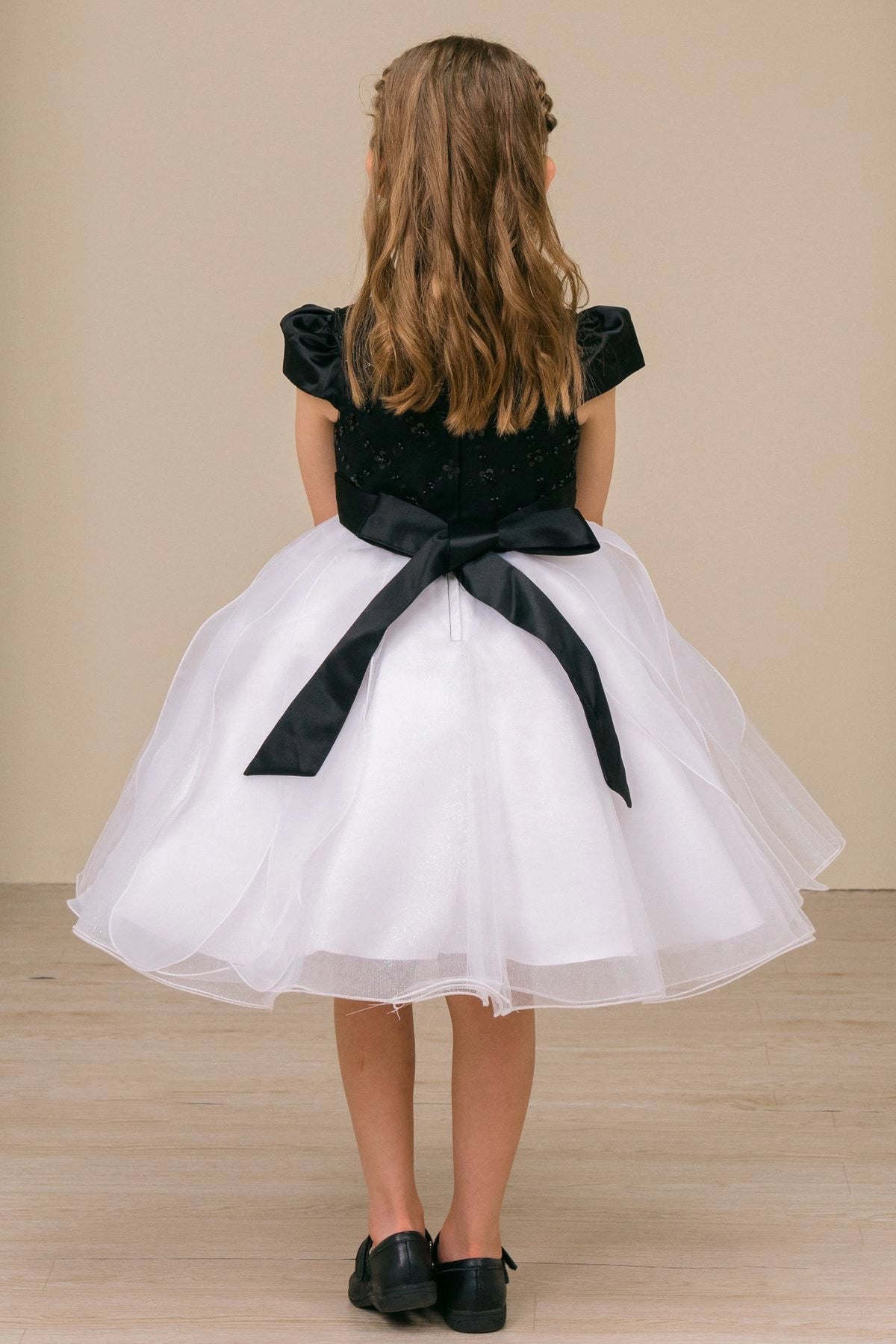 Tied black sash and a layered white skirt finish this Black/White kids party dress at the back.
