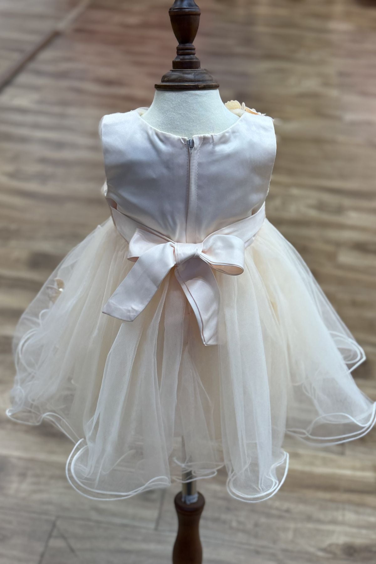 Champagne flower girl dress back view highlighting full skirt and elegant silhouette.