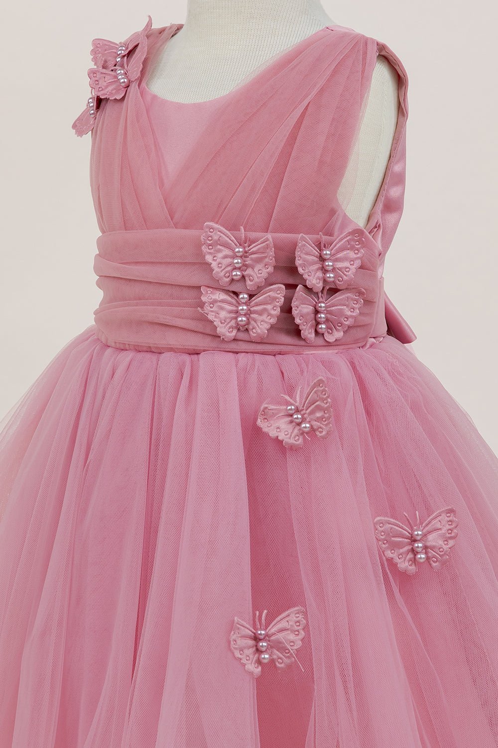 Close-up front view of rose flower girl dress showing shimmering fabric and bow accent.