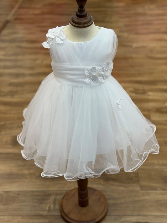 Shown in a front view, the White flower girl dress has one-shoulder floral trim and jeweled waist accent above a ruffled tulle skirt.