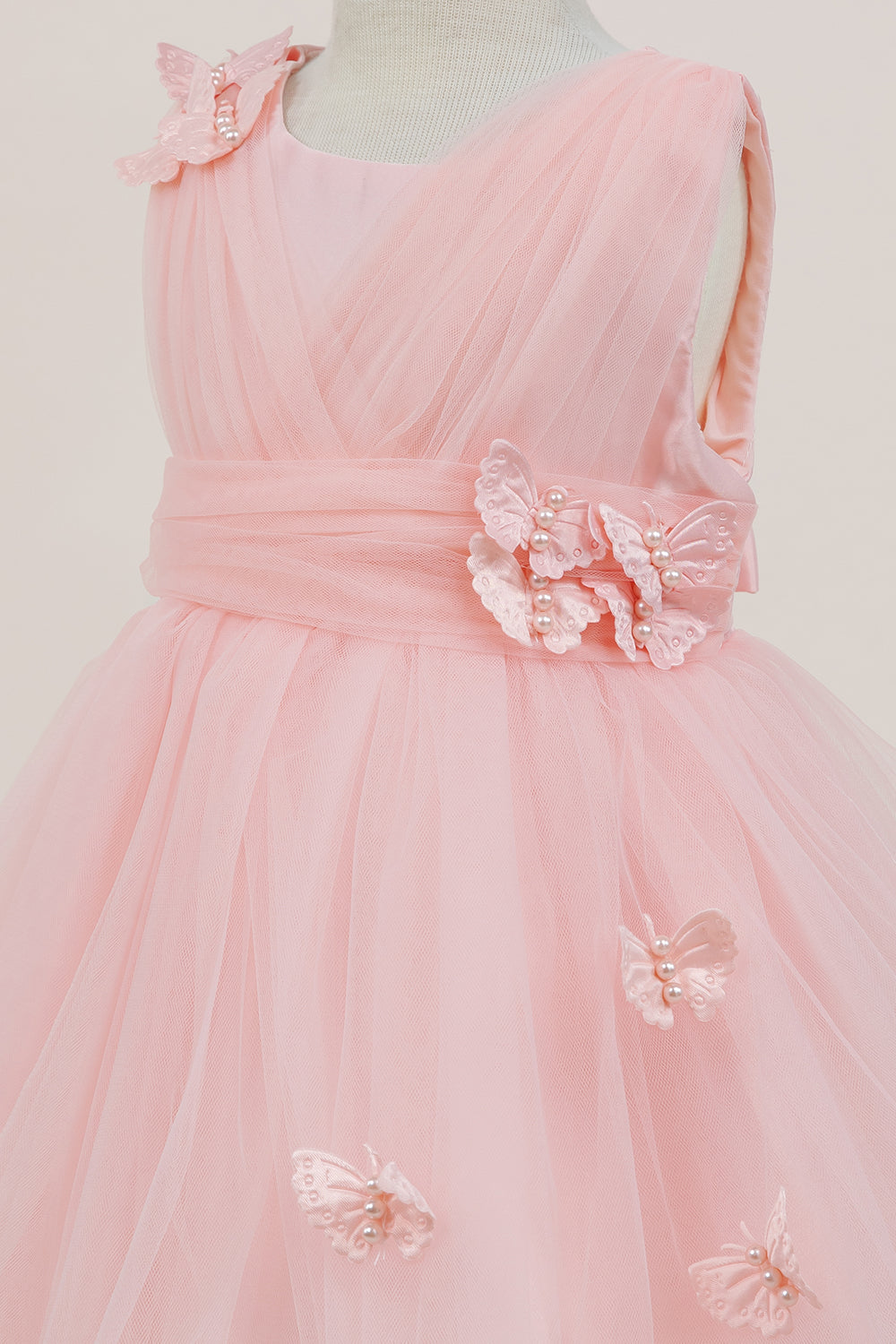 Close-up front view of peach dress showing shimmering fabric and bow accent
