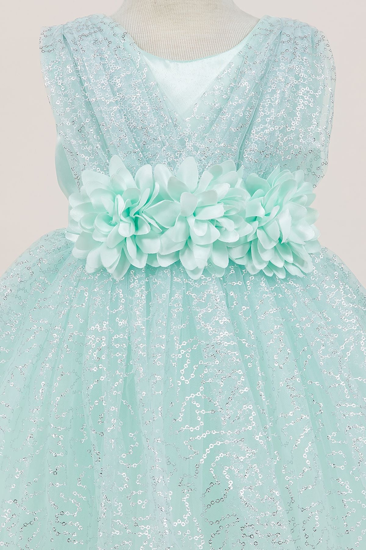 Close-up front view of mint flower girl dress showing shimmering fabric and bow accent.