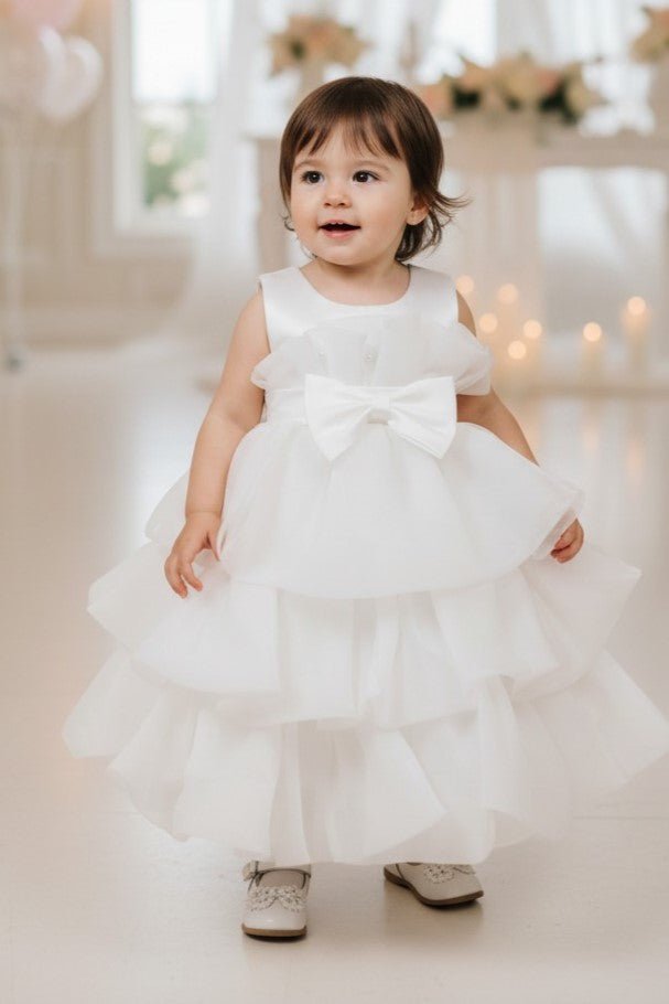 White flower girl Dress Front View With Layered Skirt And Oversized Bow Detail.