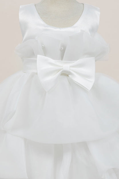 Close-up front view of white dress showing shimmering fabric and bow accent