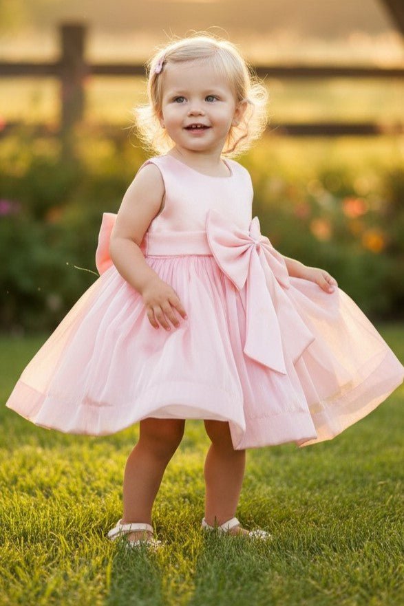 Pink flower girl Dress Front View With Layered Skirt And Oversized Bow Detail.