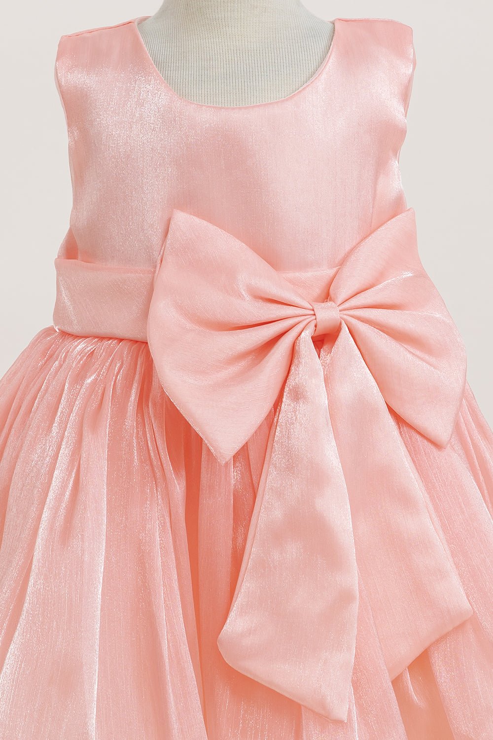 Close-up front view of pink flower girl dress showing shimmering fabric and bow accent.