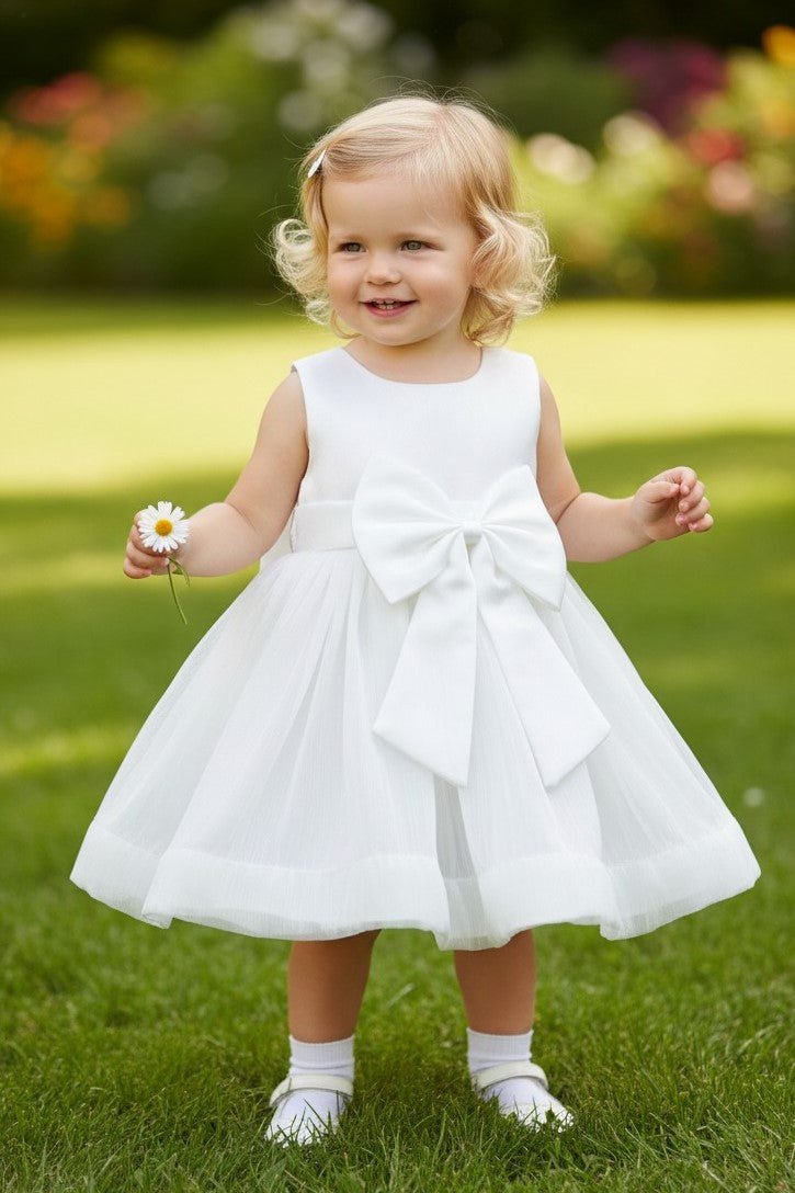 White flower girl Dress Front View With Layered Skirt And Oversized Bow Detail.