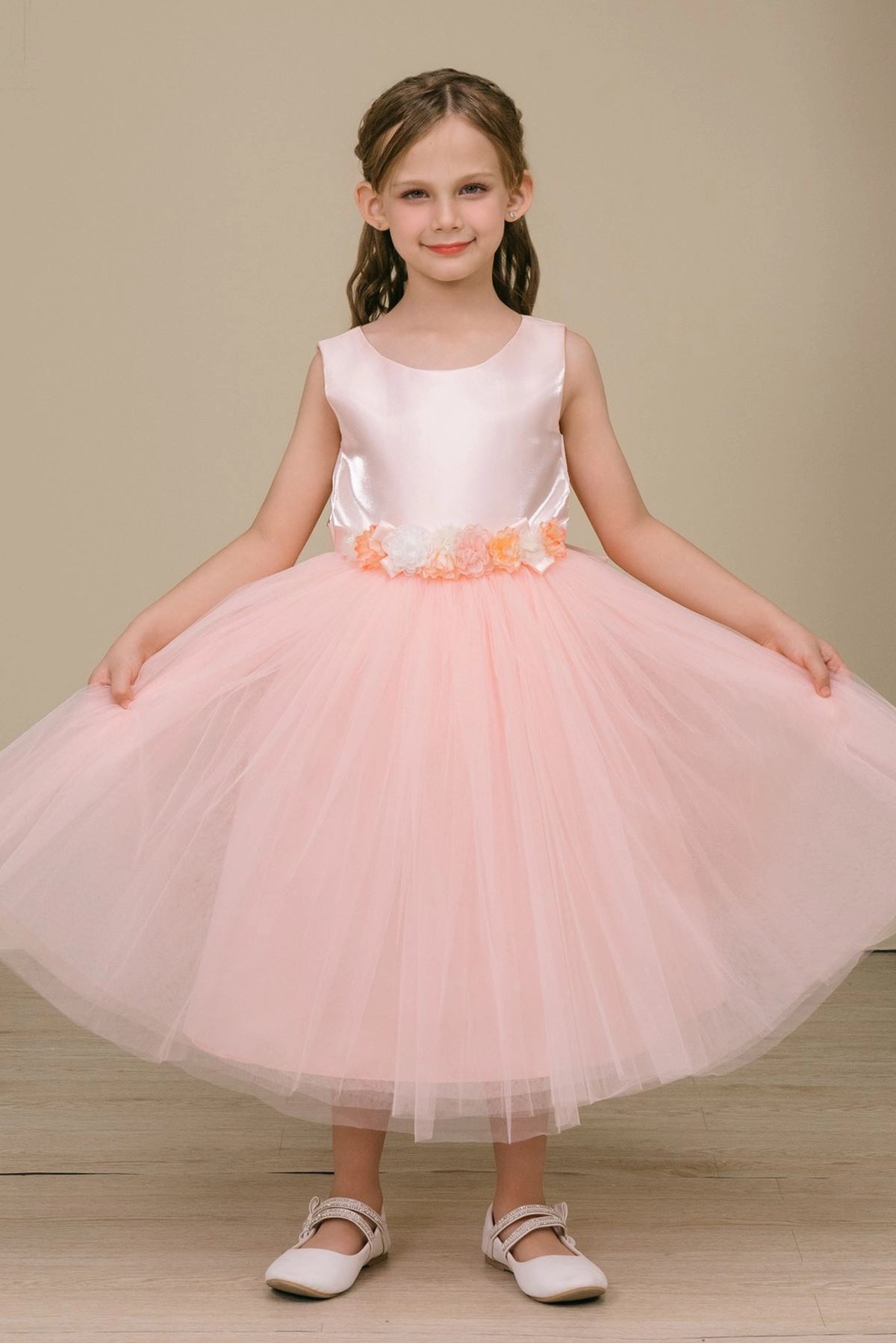Blush flower girl dress features fabric flowers above a layered tulle hem.