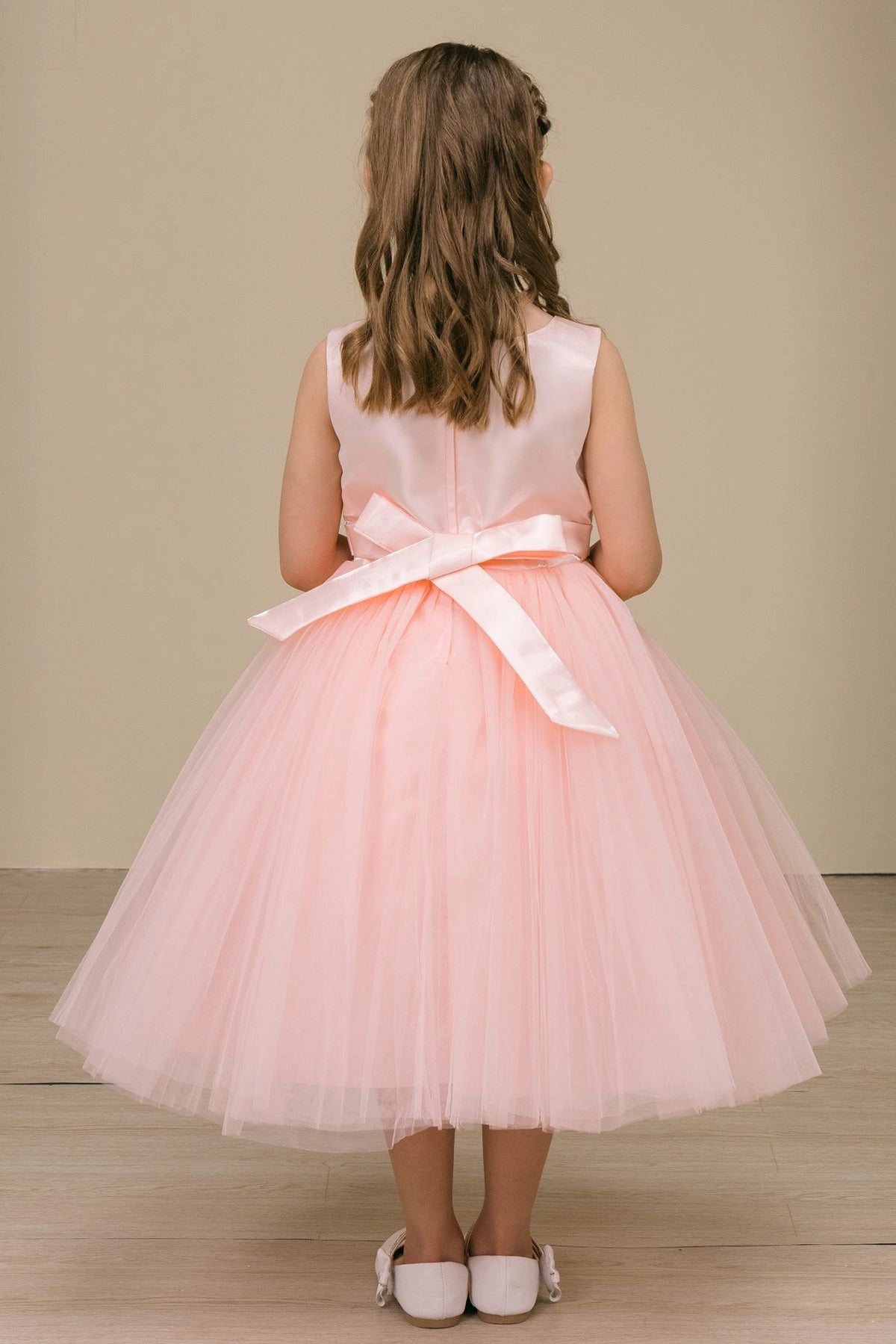 A Blush flower girl dress showing back sash bow above the layered skirt.
