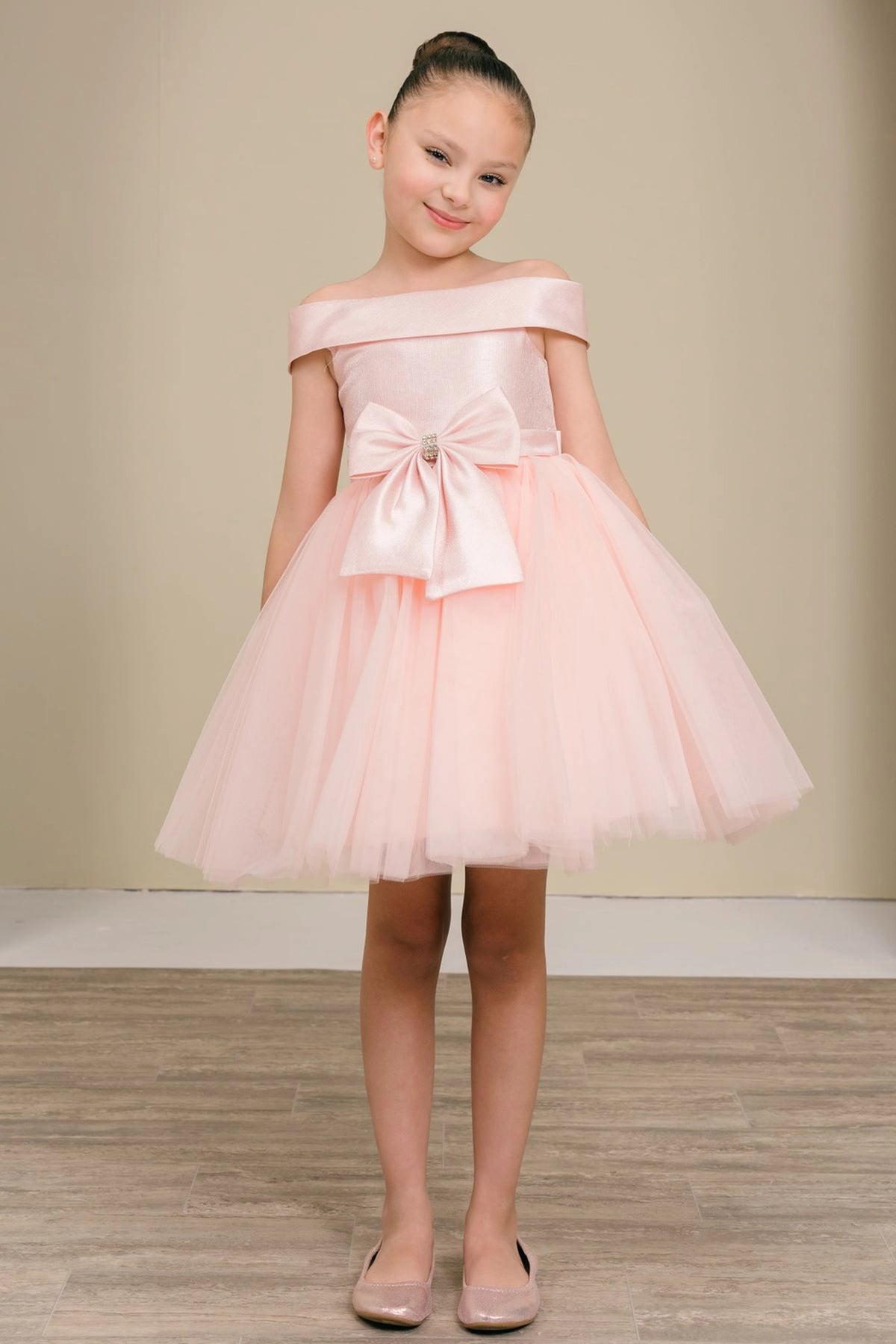 Blush flower girl dress features large front bow and layered tulle hem.