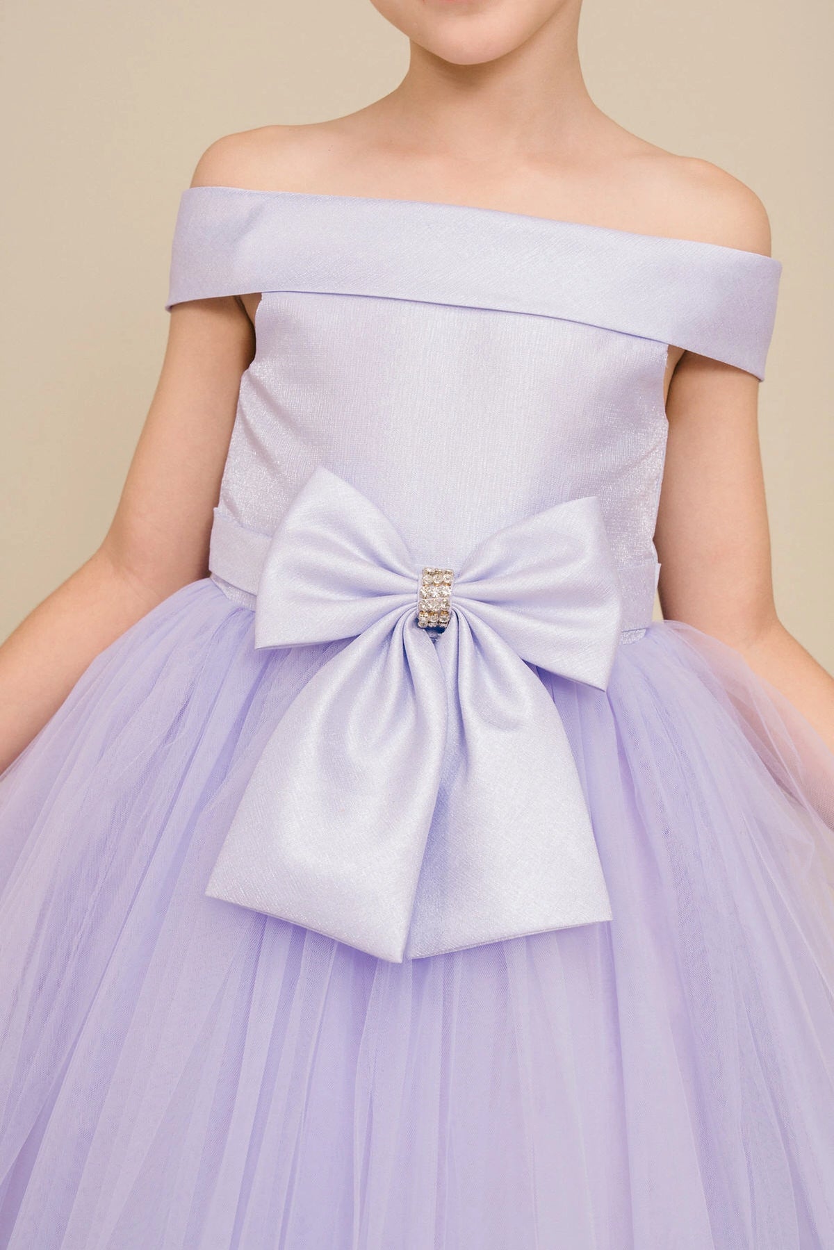 Visible on this Lilac flower girl dress: jeweled front bow beneath the folded neckline.