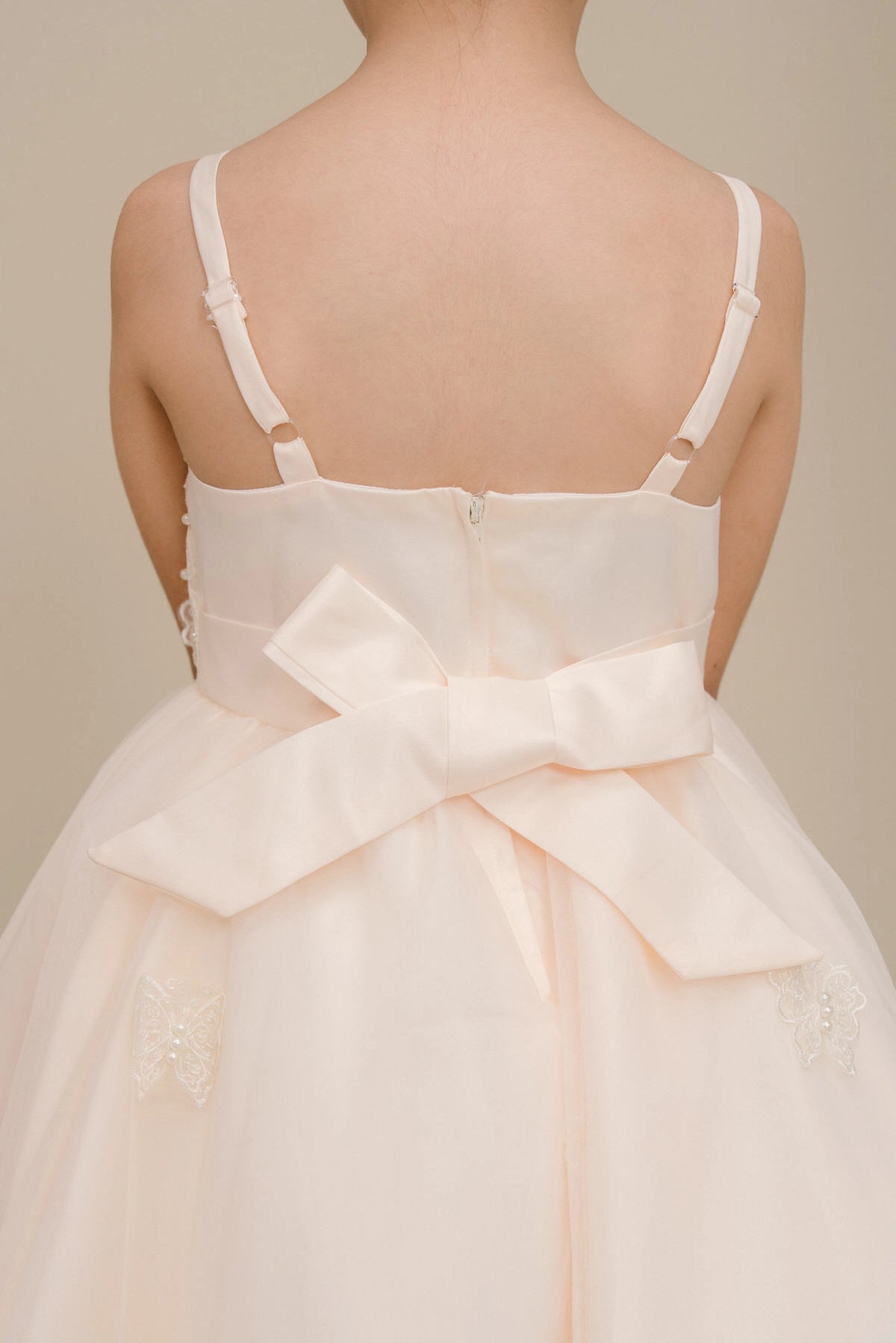 Detailed by a large bow above a high-low skirt, the Champagne kids party dress reveals its construction.