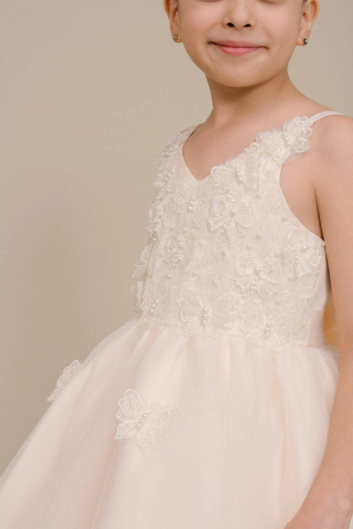Accented a tiered high-low skirt adds character to this Champagne kids party dress.