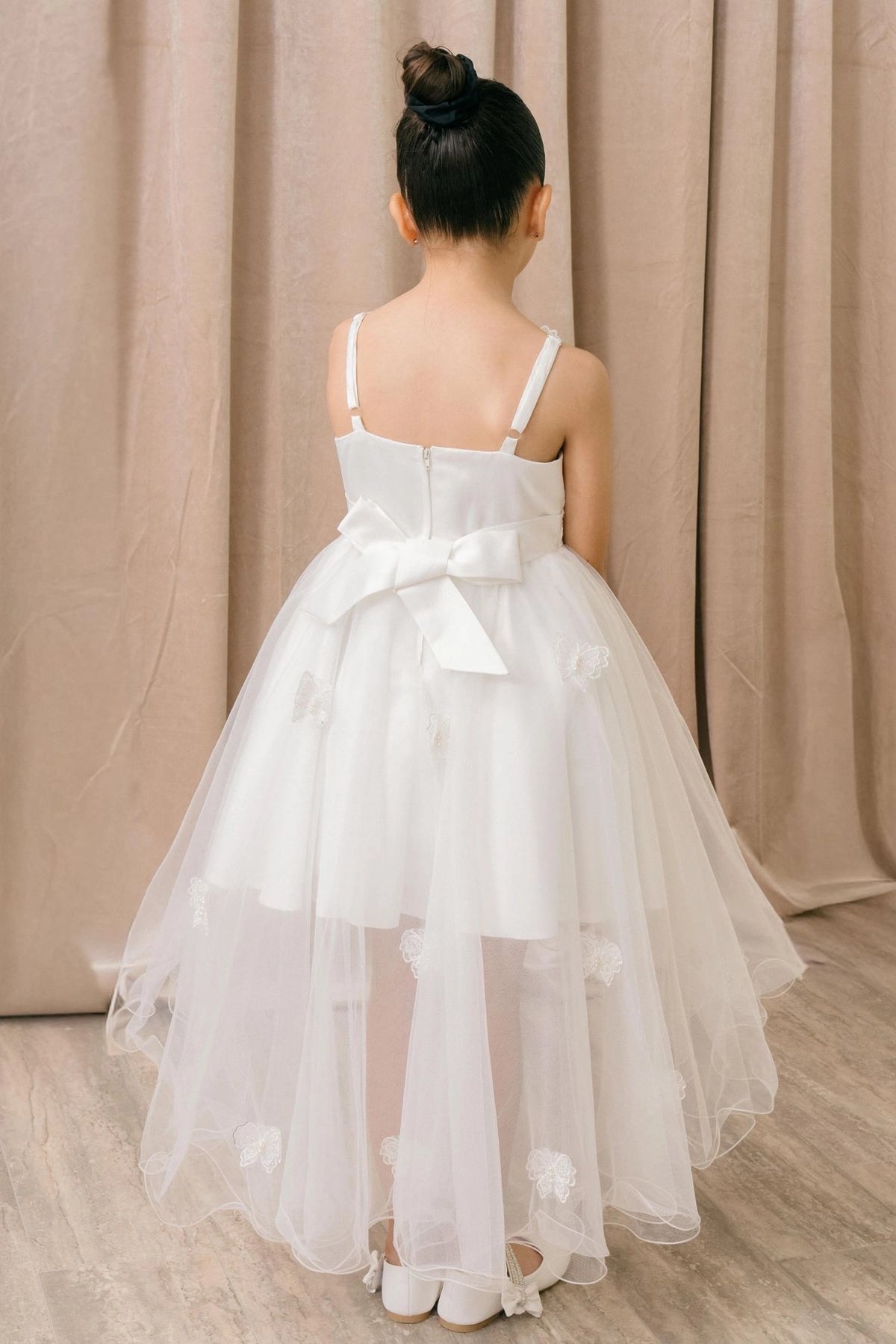 Showcasing with a large bow above a high-low skirt, this White kids party dress displays elegant detail.
