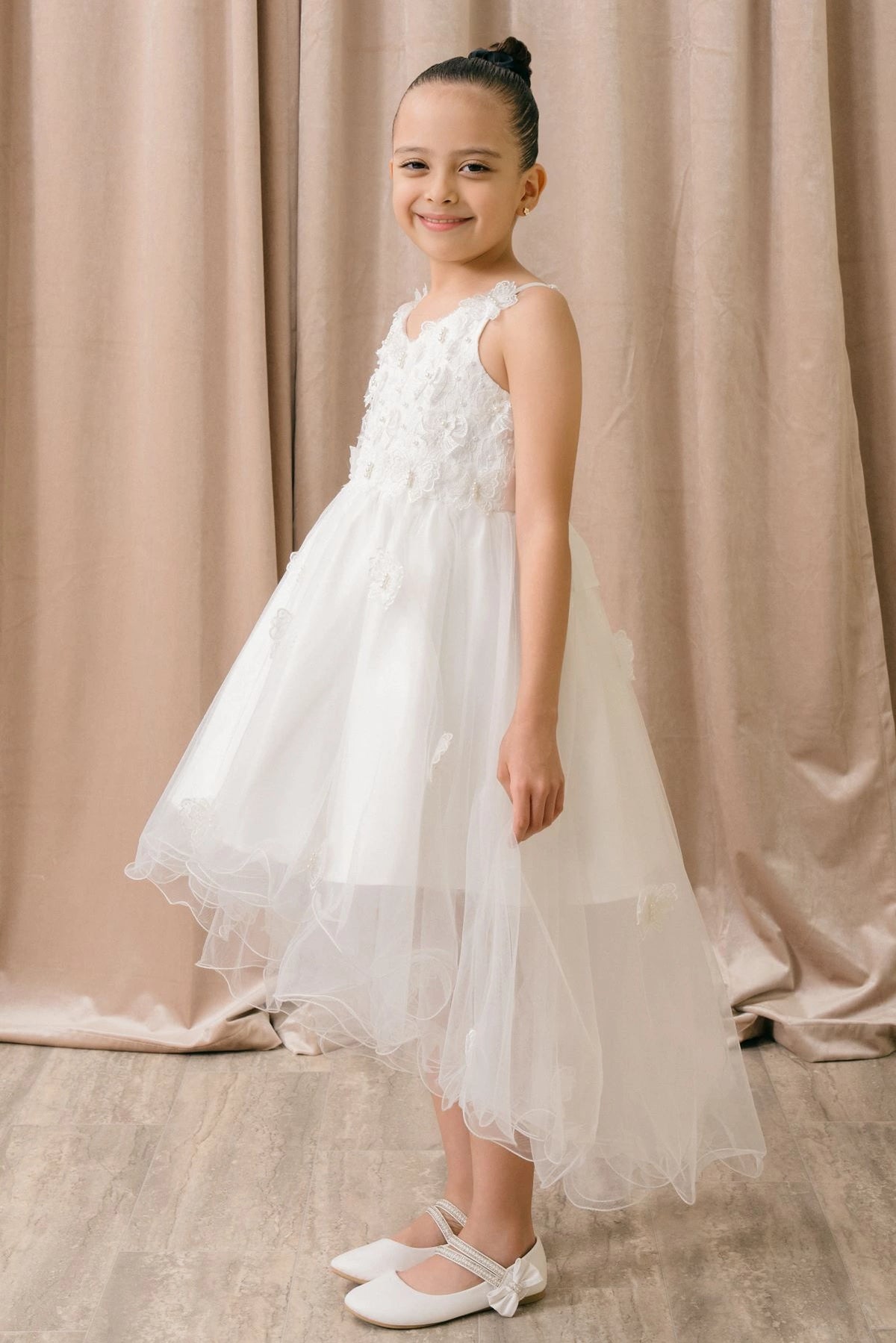 Featuring with a tiered high-low skirt, this White kids party dress displays elegant detail.