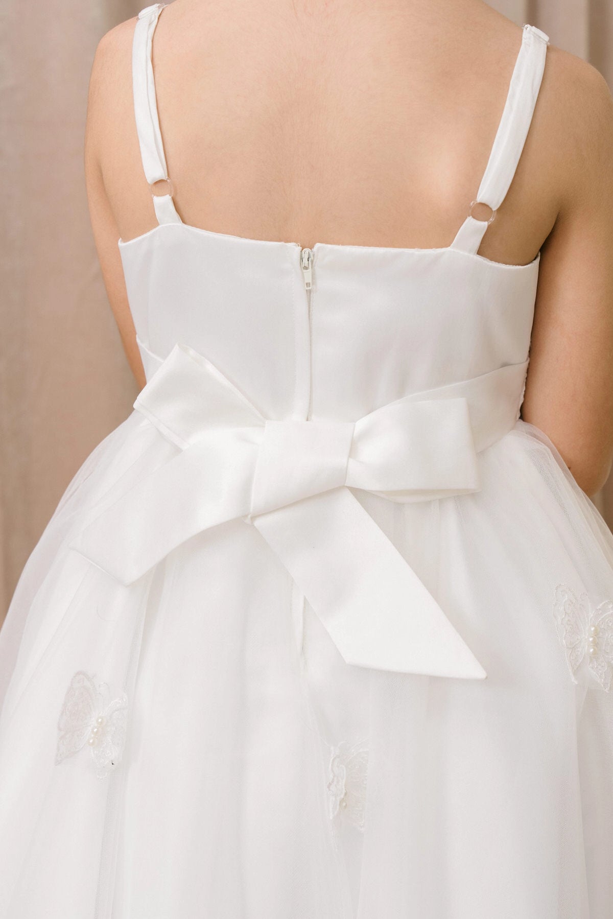 Finished details of a large bow above a high-low skirt distinguish the White kids party dress.